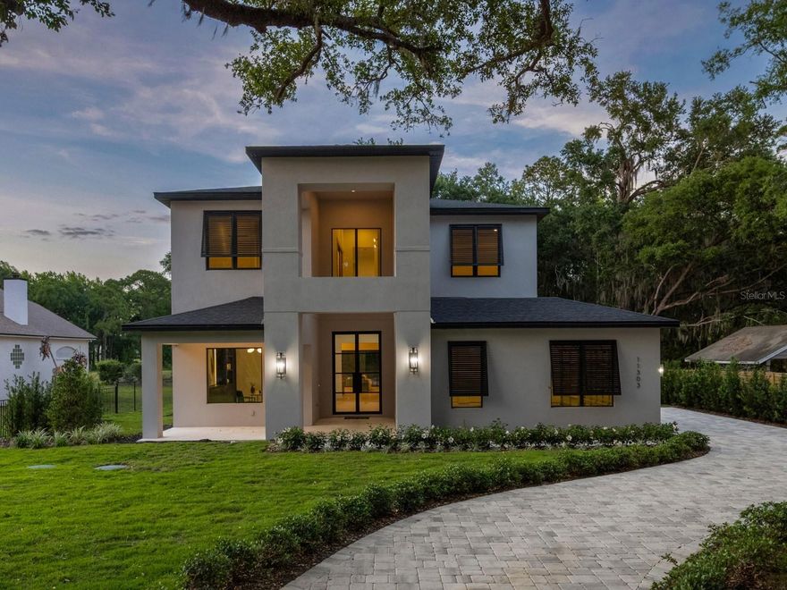 Set on an expansive, nearly half-acre lot and located just a short walk from Downtown Windermere, this brand-new construction residence delivers a level of space, design, and presence that is rarely found in Windermere. Framed by a large driveway and a three-car garage, the home makes an immediate impression before you even step inside. Through the grand double-door entry, you’re welcomed by a striking stone feature wall with LED backlighting, setting the tone for the refined design carried throughout. The main living area is both warm and beautiful, highlighted by rich wood beams, custom built-in shelving, and a statement wall anchored by a sleek electric fireplace. At the heart of the home, the chef’s kitchen is as functional as it is beautiful, featuring an oversized quartz island, a hidden walk-in pantry, and a full suite of Thermador appliances, including a paneled refrigerator for a seamless, custom look. The space flows effortlessly into the lanai through a wall of pocketing sliders, blurring the line between indoor and outdoor living. Just off the kitchen, the formal dining room makes a statement of its own with detailed millwork and a stunning wine wall that adds both style and sophistication. The primary suite is a true retreat, offering generous proportions and refined detailing, including custom millwork with soft LED uplighting. The spa-inspired bath features dual vanities, a freestanding soaking tub, an expansive walk-in shower, and a large custom closet. Also on the main level, a dedicated office with a substantial built-in provides a private and polished workspace. Upstairs, the home continues to impress with four additional bedrooms, along with a flex space that can serve as a fifth bedroom or second office. A sprawling bonus/game room anchors the upper level, complete with its own fireplace and a large island with bar seating. Outdoors is where this property truly sets itself apart. Rare for Windermere, the nearly half-acre homesite offers an extraordinary backyard framed by mature trees, creating both privacy and a sense of nature. The expansive covered lanai is equipped with a full summer kitchen, perfect for year-round entertaining. Beyond, a beautifully designed lap pool and spa are complemented by a dedicated deck area ideal for a fire pit or lounge seating, creating a resort-style environment that is almost impossible to replicate in this location. With its combination of walkability to Downtown Windermere, oversized lot, and thoughtfully curated architecture, this home represents a rare opportunity to own a truly exceptional new home in one of Central Florida’s most desirable areas.