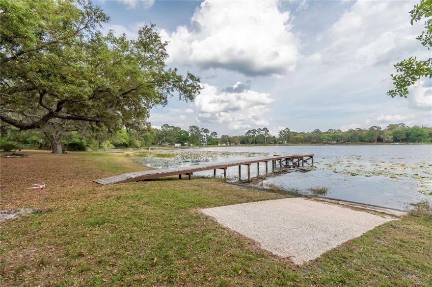 Breezy waterfront living along Miles Kale Lake! Overlooking the sparkling spring-fed Miles Kale Lake in the quiet area of Fort McCoy, this property offers a total of two parcels that feature pristine shoreline and a combined 1.12 acres. All of the acreage is fenced, with the two parcels being a gently shaded lot with the main residence and a secondary lot which has been left in a more natural state as a heavily wooded area. Move-in ready and fully furnished, this cozy lodge like Cottage rests on the eastern lot and offers plenty of sleeping space in the 1-bedroom or the spacious family room with beds for 4. This charming cottage features a large family room, a delightful kitchen with adjacent dining area, and a great screen-enclosed porch.  All rooms have a restful view of the lake. This home offers a rustic aesthetic with lots of tasteful wood-work done throughout the home. A laundry shed is also attached to the home for added ease. A private boat ramp with a recently updated dock allows for easy enjoyment of the lake, opening up a variety of uses for those who enjoy spending time on their boat. Miles Kale Lake is a wonderful, natural Florida lake with a nice sand bottom and a few unique features that make it extra exciting– the lake has a gradual slope and is deeper than many other lakes in the area. The lake is great for boating on canoes, kayaks, jet skis, as well as power boats with other boats rarely being seen on the lake to provide little to no disruption on most days. Many other lakes are also in the area, making this an ideal property for those looking to discover the many activities Central Florida has to offer! If you’re ready to take in pristine water-front views or are looking for an income producing opportunity, this property is a wonderful option to consider!