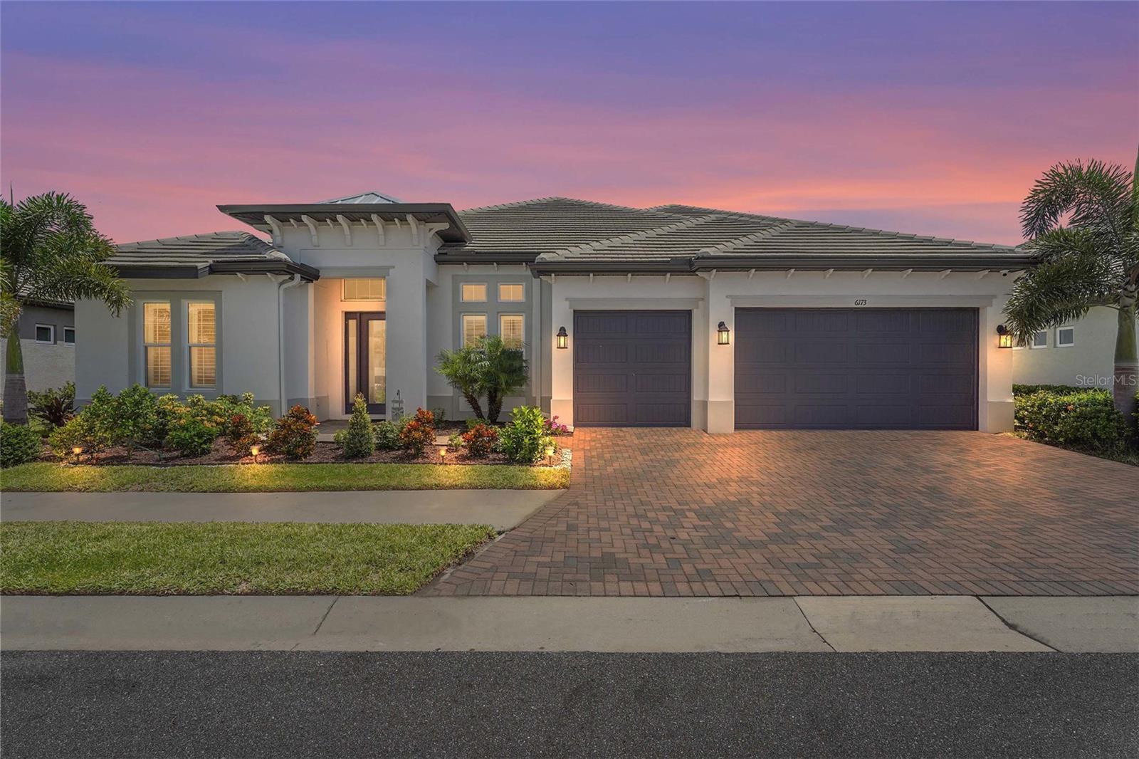 Behind the gates of the luxury Rivo Lakes community, this 2023-built 4 bedroom plus office, 4 bathroom home spans over 4,000 square feet of refined living space, complete with a 3-car garage and over $165,000 in upgrades since completion. From the moment you arrive, the pavered driveway, tile roof, and pristine landscaping create a striking first impression, hinting at the luxury that awaits within. Step inside to soaring ceilings, natural light, and a flowing open-concept floorplan designed for both elegance and everyday comfort. Just off the foyer, a dedicated office offers the perfect space to work or create, while 22-inch ceramic tile flooring stretches seamlessly throughout the main living areas. The heart of the home is the showstopping chef’s kitchen—anchored by a 12-foot quartz island with a waterfall edge, perfect for casual dining or entertaining. High-end touches include a custom hood vent built for the 36" Fulgor Milano 6-burner natural gas stove, GE Café refrigerator, white cabinetry with under-mount lighting, and a huge walk-in pantry. The owner’s suite is a private sanctuary, with plantation shutters, its own exit to the pool, dual walk-in closets, and a spa-inspired ensuite bath featuring dual vanities, a freestanding soaking tub, and a glass-enclosed walk-in shower. A split-bedroom design ensures privacy, with a guest bathroom offering a seamless glass shower, floor-to-ceiling tilework, and direct pool access. Perfect for multi-generational living, a second primary suite includes its own spacious ensuite, dual sinks, glass-enclosed shower, and a large walk-in closet with custom built-ins. Upstairs, a sprawling loft—currently a home gym—offers endless possibilities as a media room or play space, accompanied by another bedroom and full bathroom for guests or family. Step outside to an entertainer’s paradise, where the pavered, screened-in lanai overlooks a tranquil pond—a waterfront oasis. Relax by the sparkling heated saltwater pool and spa, all while enjoying music from a premier Sonos system that flows effortlessly from the dining room through the kitchen and family room, then out onto the lanai and pool area. Marine-grade outdoor speakers perfectly complement the setup, delivering crisp sound right where you want it most. The impressive newly added 12-foot outdoor kitchen seats eight and includes two grills, bar setup, two refrigerators, and a wine fridge—perfect for hosting unforgettable gatherings. The outdoor kitchen also features its own Bluetooth radio and speakers, along with multi-colored lighting that spans underneath the center island. Additional features include a whole-home Generac generator, IMPACT WINDOWS, large laundry room with added cabinetry and sink, LG washer and dryer with pedestals, no CDD fees, and low HOA fees. Ideally located just 15 minutes from Siesta Key Beach, near Myakka State Park, St. Armands Circle, the UTC Mall, and top-rated schools including the new Sky Ranch K-8 opening Fall 2025. Twin Lakes Park, with 123 acres of lakes, trails, playgrounds, and sports fields, is just moments away. Experience the unmatched elegance and lifestyle this Rivo Lakes home offers and schedule your private showing today.