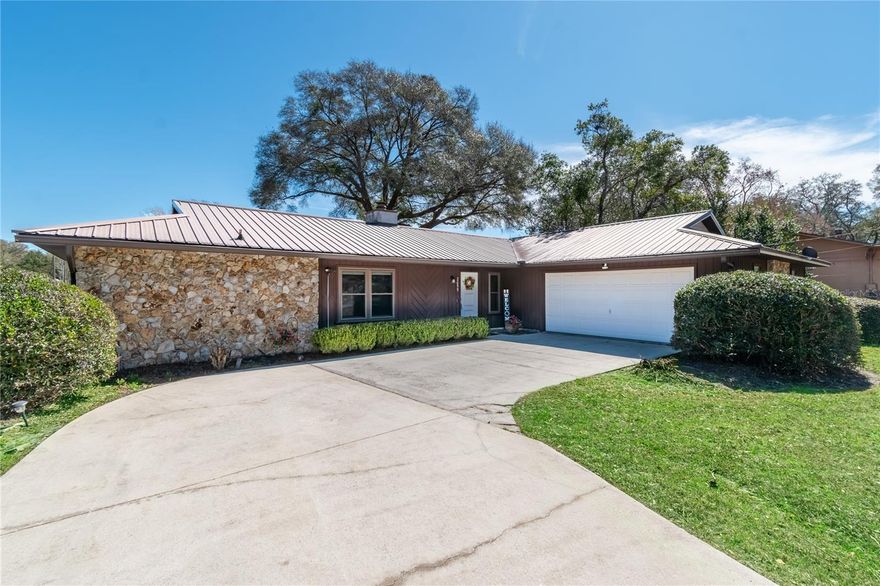 Resting on a spacious corner lot within the established Pine Oak Estate community, this charming ranch-style home is an inviting option with plenty to discover. Overlooking large yards and surrounded by mature landscaping, the 3-bedroom, 2-bath home offers just under 1,800 sqft of thoughtfully designed space. Vaulted ceilings and wood flooring run throughout the majority of the main spaces, creating a relaxed, airy atmosphere. Large windows provide abundant natural light throughout, while the split-bedroom floor plan ensures plenty of privacy when you’re ready to unwind. The heart of the home is the expansive great room, where a striking wood-burning fireplace creates a warm and welcoming focal point, perfect for relaxing evenings or gathering with guests. The kitchen provides abundant counter and cabinet space, a breakfast bar, and easy access to the adjacent family room. The primary suite is comfortably sized and privately situated, featuring a built-in closet and an en-suite bath with dual sinks and a walk-in shower. Two additional bedrooms provide flexibility for guests, a home office, or creative space if desired. Outdoors, enjoy a fully fenced backyard with chain-link fencing, mature trees that offer natural shade, and a patio ideal for outdoor dining or quiet mornings with coffee. Located just down the road from Maplewood Elementary and convenient to a variety of shopping, dining, entertainment, and outdoor recreation options, this property is an amazing opportunity to enjoy comfortable living in a well-established Ocala neighborhood– all with NO HOA fees!