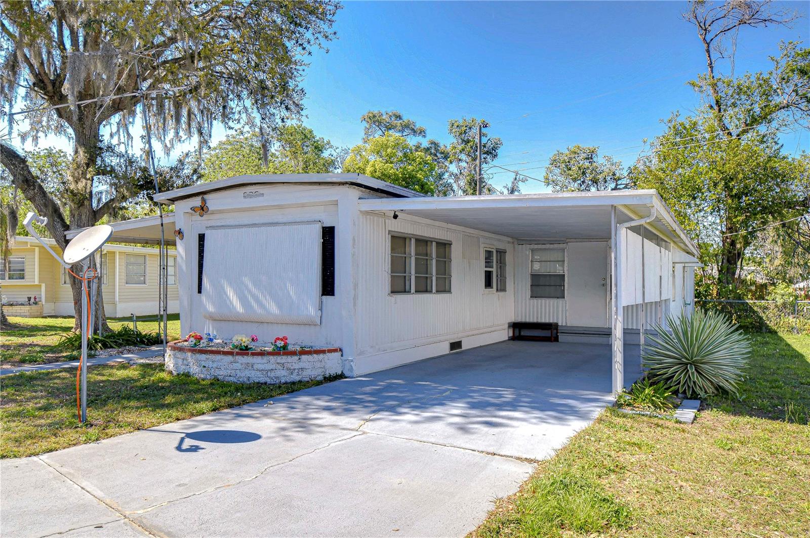 Near the clubhouse for your convenience. Enter into the enclosed porch or Florida room and on into the home. You have an open
area of the furnished living room and kitchen with an eating area. The home is furnished. You only need to bring your personal items.
Down the hall are smaller storage closets or maybe even a pantry. The hall bath has a tub with a shower and a linen closet. The
bedroom at the end of the hall has a built in closet and built in dresser and vanity area. To the right of the hall is the addition with a
large bedroom and another bathroom with a tub with a shower. Off of the Florida
room there is a workshop area. Out back there is a shed attached with the laundry area. This home has a carport and driveway for
parking. Call now for an appointment to view this home.