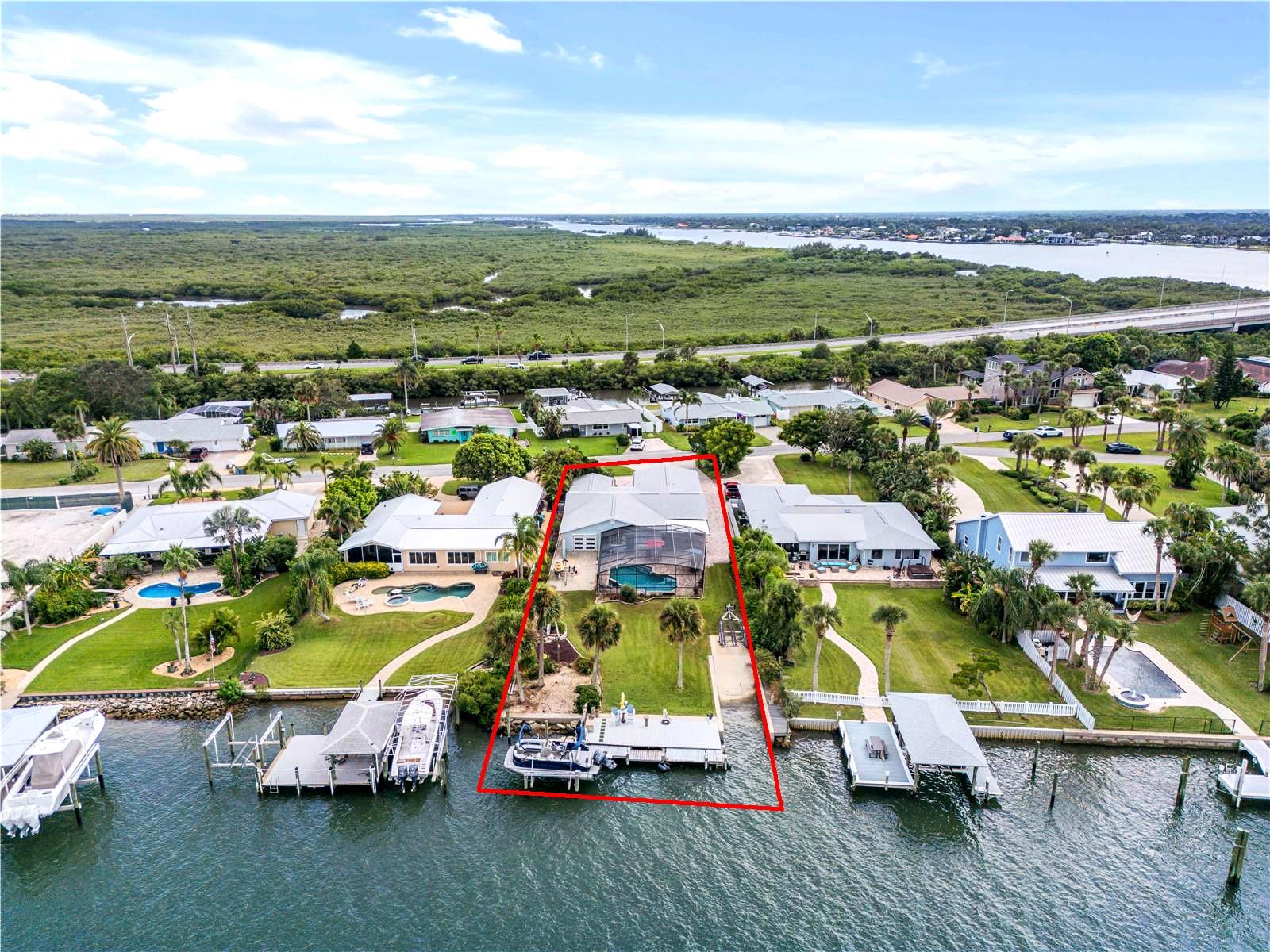Coastal living with 76’ of Deep Water frontage directly on the Intracoastal waterway. Plus your private 10’ wide boat launch,13,000 LB boat lift, large swimming pool and spa. You cannot find a better location than this! Centrally located in beautiful New Smyrna Beach on a quiet cul-de-sac just moments away from the sandy beach, famous Flagler Avenue and historic Canal Street. A home with a panoramic view and amazing sunsets. Walk into a home with exquisite hardwood cherry flooring installed in 2015, the large foyer has custom wood book-shelves and a Murphy bed. This spectacular home is perfect for the entire family! Not only does this home have everything for the boating enthusiast it also has plenty of room for entertaining friends and family. The home is currently set up to sleep up to 11 people comfortably. The delightful designer kitchen with tray ceiling, countertop seating, quartz countertops, wood cabinetry, and top of the line stainless steel appliances completed in 2015. The kitchen opens up to the dining area overlooking the large screened outdoor kitchen, pool and spa area with plenty of seating overlooking the Intracoastal waterway. The beautifully landscaped garden is complete with an Olive tree, two Mulberry bushes and pineapple plants. The primary bedroom has a private en-suite bath and an adjacent room that can be used as a dressing room, office or craft room with closets, the guest bedroom also has a private en-suite bathroom. The bunk bed/kid room with a closet and laundry facilities is located just off the kitchen. The Riverview third bedroom/office is located to the east of the main living room with views of the intracoastal waterway. The room has a garage door and motorized screen to enjoy the river breezes. This home is on a very large lot that can accommodate parking for up to 8 to 10 vehicles plus an oversized 2 car garage. Renovations adding the master bedroom and 2 car garage that was completed between 1995 and 1999. New Roof 2022, 2 A/C units new 2022 and 2023, updated reinforced seawall 2023, propane heated Spa (spa heater 2 years old), plus new tankless water heater 2025. Location Location, Location walk, bike or short drive to the soft sandy beach, 1 mile to the famous Flagler Avenue with shopping, restaurants, bars and nightlife or 1 mile west to Canal Street with more shops, restaurants and bars. This home is a must see to truly experience the beauty, functionality and the perfect location here in New Smyrna Beach.