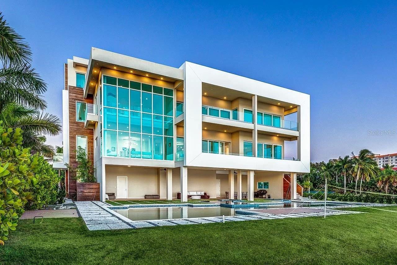 WATERFRONT MANSION with DEEP WATER DOCK in a GATED COMMUNITY only ONE MILE AWAY FROM DOWNTOWN! Built in 2017 to stand Florida hurricanes, this modern property stands on 75-concrete-pile foundations, all concrete exterior walls/slabs/roof, impact glass windows, and more. Enjoy stunning views of Downtown, the Ringling Bridge and the Sarasota Bay from the many large waterfront balconies. The house features a deep water dock with a 13,000lbs boat / jet ski lift. Relax in the resort style pool, featuring a 12-people spa and a large sunshelf. Luxurious finishes, including sidings made of Brazilian Cumaru, modern interior doors from Italy, German kitchen, and Porcelain tile from Spain, contribute to the home's modern elegance and sophistication. A few other notable features include: walk-in wine cellar, full home automation system, elevator serving all floors including roof, and much more.