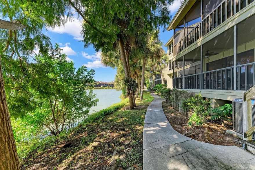 Discover easy Florida living in this inviting first floor condo in the desirable Lake Arrowhead community of Sarasota, offering residents a gorgeous heated community pool, a clubhouse with lakeside views and guest parking available for visitors. Just steps from the Red Bug Slough Trail, you’ll enjoy immediate access to beautiful nature paths and shaded walkways. The community is also only a few miles from world-famous Siesta Key Beach and close to shopping, dining, and entertainment.

Inside, you will find a welcoming, light, bright and airy feel to welcome you. Light laminate flooring extends through the entry hallway, kitchen, and dining nook, while tile flooring enhances the main living area. An open floorplan and high ceilings create a spacious environment, with a clear sightline from the front entry straight through to the large, private, screen-enclosed lanai with peaceful lake views. The lanai is accessible from both the living room and the primary bedroom, and the views of the lake and brings the serene setting right to your back doorstep.

The kitchen features a generous passthrough opening to the dining and living area, offering excellent flow for everyday living and entertaining. Granite countertops, rich redwood Shaker cabinets, stainless steel appliances, and an in-kitchen dining nook create a warm and functional space, with a bar top seating option for added flexibility.
The primary bedroom suite enjoys peaceful water views and direct access to the lanai through sliding glass doors. Its en-suite bath includes a separate vanity area and a private toilet and shower closet for convenience. The spacious guest bedroom can be accessed from both the hallway and the main living area, and the guest bathroom offers a large vanity and shower/tub combo.
Additional features include a laundry closet conveniently located near the kitchen, and carport parking with an attached shed for added storage.
Blending comfort, convenient access to Sarasota’s best attractions, and natural beauty, this lakeside retreat is ready to welcome you home. Wake up to water views, step into nature, and live the relaxed Florida lifestyle you’ve been dreaming of!  Come see, come sigh and make this home your own.