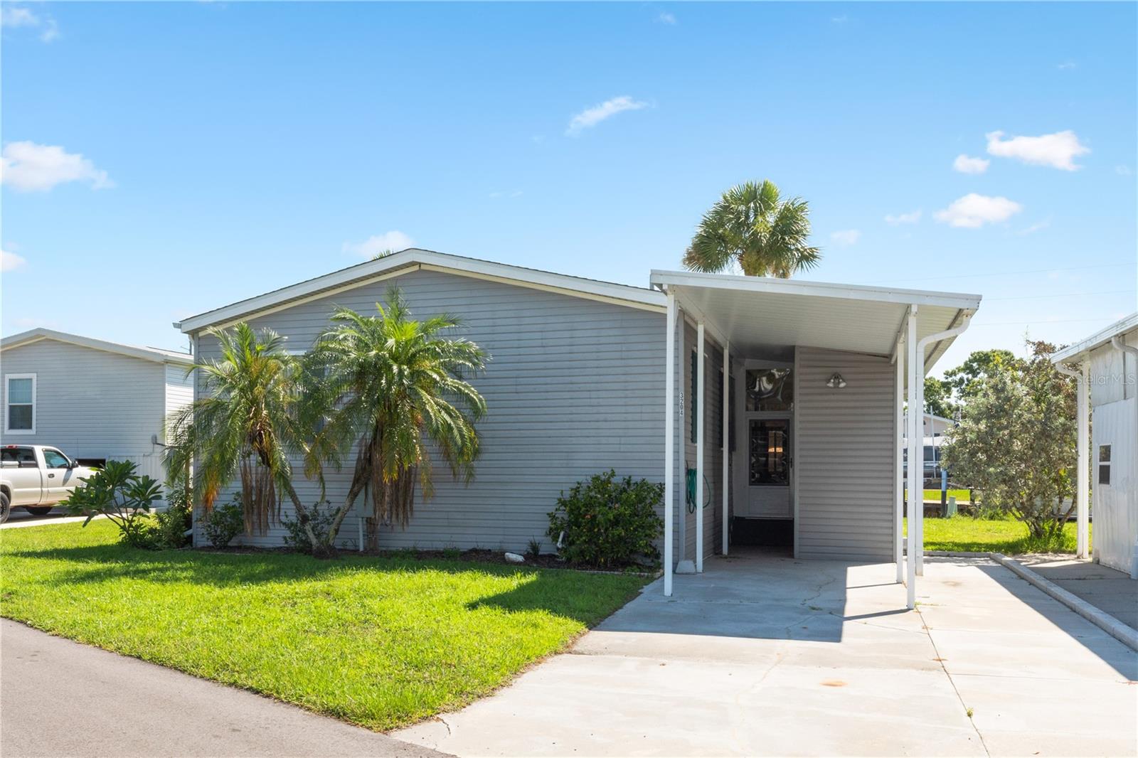 CHARMING WATERFRONT FURNISHED 3 Bedroom, 2 Bathroom, Carport manufactured home with a Florida room and 68 feet of waterfrontage located in the active 55+ Pelican Harbor mobile home community. CLICK ON THE VIRTUAL TOUR LINK 1 FOR THE VIDEO AND VIRTUAL LINK 2 FOR THE 3D TOUR. Spend quality time with friends and family in the open living room while whipping up family favorites in the kitchen. The EAT-IN kitchen offers ALL stainless - steel appliances, granite countertops, and a breakfast bar. The master bedroom has a walk-in closet and a private bathroom with a dual sink vanity and a walk-in shower. The guest rooms have built-in closets and a shared guest bathroom nearby. Cast your line or launch your kayak for endless water adventures from your backyard with a concrete sea wall with plenty of room for a dock and boat lift. Expand your living and entertaining space to the screened lanai, where you can sip your morning coffee or unwind with your favorite evening beverage while enjoying the BEAUTIFUL water view. Pelican Harbor is an active waterfront community with a clubhouse, community pool, shuffle board, and RV & Boat storage. Schedule your showing TODAY!