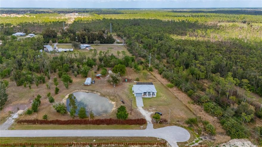 Tucked back for added privacy and quiet! This 5.58-acre retreat borders a 2,331-acre nature preserve and is located at the end of a quiet road.  The bright 3BR + Office pool home features a separate luxury outbuilding ideal for a studio, gym, or entertainment hub. The outdoor oasis includes an expansive lanai with a pool and fridge, a wooden playset, a charming chicken coop and a pond. A true country sanctuary designed for entertaining and peaceful living. This home mirrors the perfection of a model home, featuring a soft neutral palette and soaring high ceilings that enhance the sense of space. Upgraded tile flooring flows seamlessly through the open-concept heart of the home, connecting the gourmet kitchen to the expansive living and dining areas. Designed for privacy, the split-bedroom floor plan offers a quiet retreat from the main social hubs.