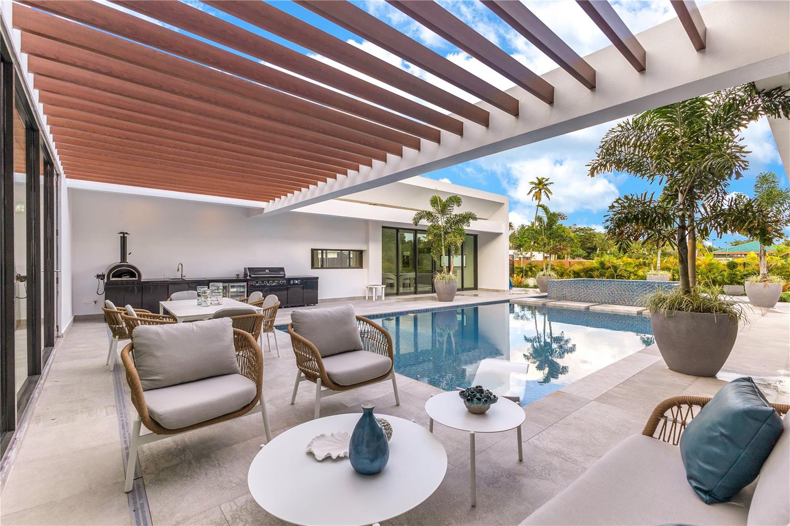 Situated in one of Dorado Beach's most desirable neighborhoods, known for exceptional value in custom homes, this 10,385 sq. ft. new construction estate exudes serene luxury. A tranquil courtyard pool with a cascading waterfall sets the tone for resort-style living. The home features six spacious bedrooms, including four on the main floor with ensuite baths and custom closets. Upstairs, a cozy living area features a bar equipped with a Sub-Zero wine fridge, refrigerator, and ice maker. The expansive primary suite boasts a sitting area, custom Italian walk-in closet, and a spa-like bath with dual showers and a freestanding tub. Additional highlights include an exterior BBQ kitchen with a pizza oven, a wet bar by the dining room, and a hidden pantry, all thoughtfully designed for unparalleled comfort and sophistication