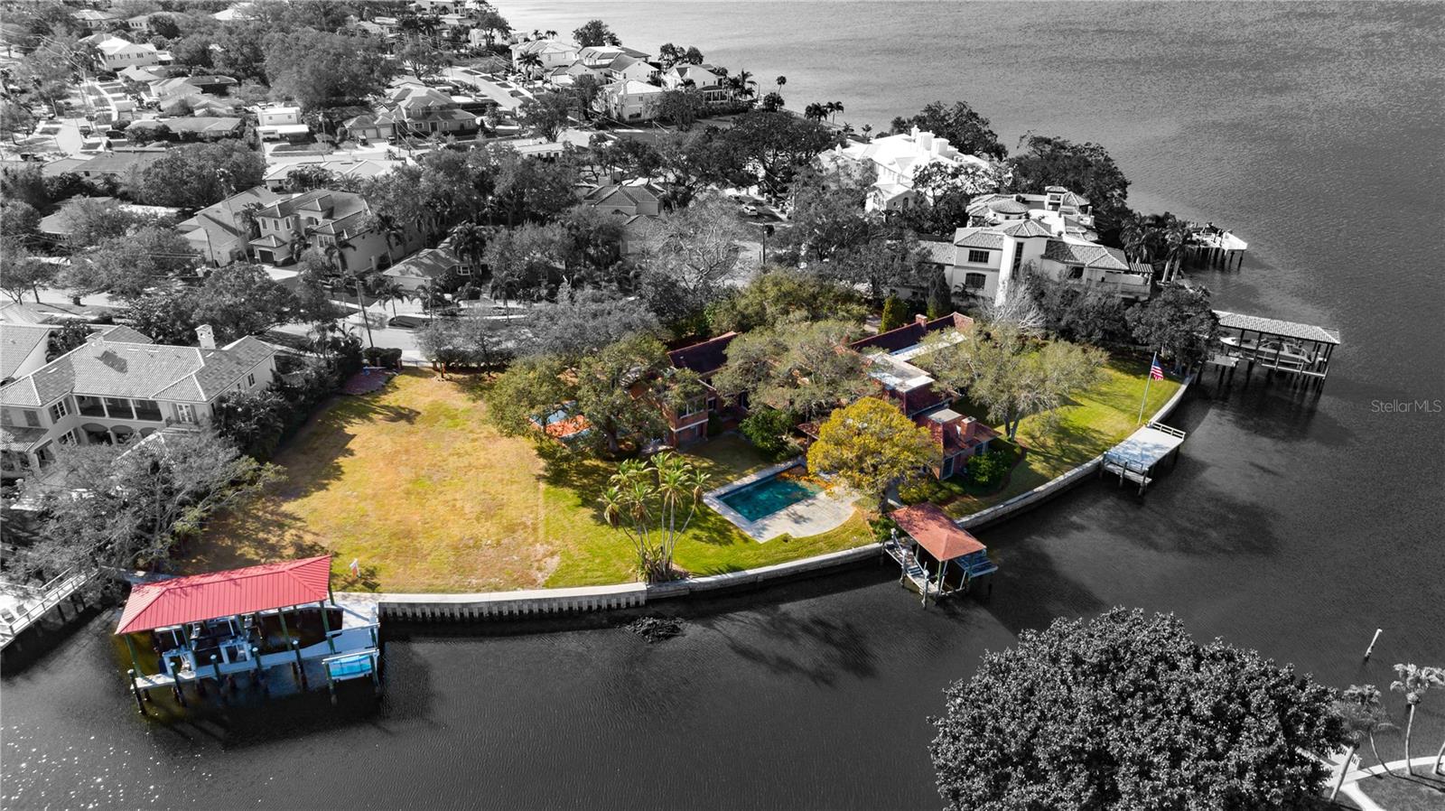 Introducing an unparalleled opportunity to own the LARGEST WATERFRONT ESTATE on Davis Islands to come on the market in decades. With an astounding 464 FEET OF WATERFRONT and sprawled across 1.45 ACRES of prime real estate, 42 Ladoga stands out as the most remarkable property on the most prestigious street in Tampa Bay's Davis Islands neighborhood. This classic Tudor home is comprised of 9,038 SF with 7 bedrooms, 7 full and 2 half baths, entertainment lounge, exercise room, library, study, pool, and sport court. Experience the ultimate waterfront and boating lifestyle with direct access to the Bay and Gulf of Mexico. This exquisite estate boasts not 1, not 2, but 3 distinct docks, each offering a unique and opulent experience for the discerning water enthusiast. Most notable among these is the magnificent boathouse, replete with 2018-built Trex dock and 2 lifts, including a 55-foot, 80,000-pound Neptune boat lift, and 13-foot, 6,000-pound multi-use lift. This boathouse is capable of accommodating a luxurious 50-foot Hinckley yacht, making it an unrivaled waterfront feature. The 2nd, more modest boathouse offers charming dock area and 2 additional lifts, while a 3rd Trex observation dock provides an unparalleled vantage point for basking in the breathtaking waterfront views. Built in 1928, this home has received several upgrades and additions during its history. Beautiful millwork, hardwood flooring, crown molding, 3 fireplaces, and host of other high end details are found throughout. Overlooking Tampa's prized waterfront, the estate-sized family room features wood-beamed ceilings, fireplace, and full bar. With multiple entertaining areas, this home's size is both impressive and inviting, with a designated 1st-floor wing accommodating a formal living room, exquisite wood-paneled executive office, and entertainment lounge with bar and bath. Gourmet kitchen features appliances fit for a chef, built-in banquette, massive central island with marble countertop, wine cellar. Off the kitchen is guest suite/media room with a private en-suite bathroom. Upstairs, the lavish owner's retreat exudes elegance with gas fireplace, study, 2 generously sized custom closets, and bathroom with stunning Bay views, as well as 4 spacious bedrooms, 2 of which are en-suite. 2nd staircase was added, providing access to separate wing with gym and guest room. Expansive grounds provide a tranquil settings with towering trees, pool, outdoor kitchen with plenty of space for hosting large gatherings. Portion of the seawall has an approx. age of 5 years. Dimensions of the entire parcel is 464' water X 240' front X 202' west X 160' east per prop. appraiser website. Davis Islands is located in close proximity to the best Tampa has to offer: Tampa Riverwalk, Amalie Arena, restaurants, shopping, downtown. Davis Islands is golf cart-friendly with dog park, Airport, DI Yacht Club, Tampa General Hospital, tennis complex, pool, commercial district with shops and restaurants, and “A” rated public schools: Gorrie, Wilson, Plant. Having a waterfront home is like constantly being on vacation.