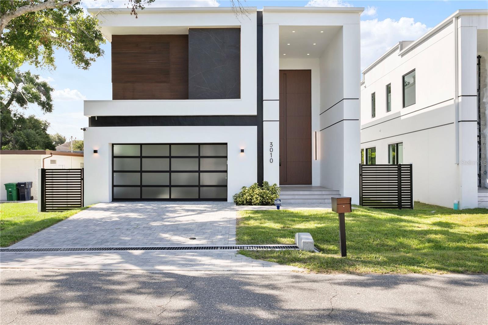 Discover a stunning contemporary residence offering an exceptional combination of cutting-edge design, energy efficiency, and luxurious finishes in this newly constructed two-story home. The property, developed by Arjen Homes, contains approx 3,600 sq. ft. of living space, featuring 4 bedrooms, 4.5 bathrooms, and an open layout designed for both comfort and sophistication. The exterior showcases a sleek smooth stucco finish accented with brick veneer and wood cladding, creating a striking modern façade, while the solid block construction and TPO roof system with R-11 insulated foam boards ensure superior durability and performance. Custom ES aluminum-framed windows with tempered glass and low-E coating add energy efficiency and elegance. Step inside through the massive 20’ pivot-style front door to an expansive open floor plan with 11’6” ceilings, a floating staircase, and imported large-format porcelain tile flooring that seamlessly connects indoor and outdoor living spaces. The chef-inspired kitchen boasts sleek flat-panel cabinetry, premium finishes, and a dining area filled with natural light from oversized picture windows, while the living space includes linear AC vents, stealth acoustics speakers, and integrated smart wiring. The luxurious primary suite offers a spa-style bathroom with floating vanities, frameless glass shower, and soaking tub, complemented by floor-to-ceiling designer tilework. Interior details include 8-foot solid wood doors with Emtek hardware, a powder bath with resort-style finishes, and modern accents throughout. Additional highlights include pre-wired security cameras for 360° coverage, two Navien tankless water heaters with recirculating system, natural gas connections, underground electric service with dual panels, and a 60” Halo 5 water softener system. Located in the heart of South Tampa near Bayshore Boulevard, Ballast Point Park, and Tampa Yacht & Country Club, this home delivers the perfect blend of modern elegance, efficiency, and convenience in one of Tampa’s most desirable neighborhoods. Schedule your private tour today and unlock the door to this exceptional opportunity!