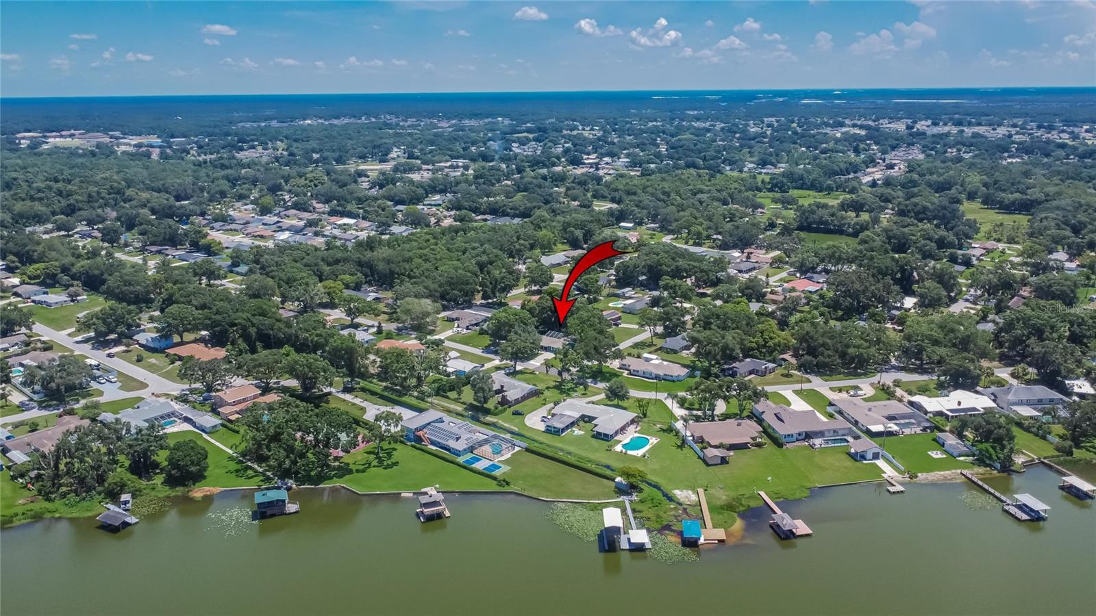 Welcome to this spacious and inviting home located on a picturesque, tree-lined corner lot directly across from the serene waters of Lake Gibson - a view you can enjoy from your front yard every day. With no HOA, this property offers freedom and flexibility in one of Lakeland's most peaceful, established neighborhoods, known for its quiet streets and friendly neighbors.. Step inside and discover a layout that surprises with its space and versatility. With two master suites, this home is ideal for multi-generational living or an in-law suite setup. The moment you enter, the home opens up into a large Great Room filled with natural light, featuring a striking stone-covered wood-burning fireplace - perfect for cozy evenings and adding a touch of auditory warmth and ambiance. The open-concept kitchen is a chef's delight, complete with stainless steel appliances, and a stylish tile backsplash. A breakfast bar create a welcoming space for casual meals or morning coffee. There's also a separate family room and living room, offering flexible space for entertaining or relaxing. All secondary bedrooms are at the opposite side of the home and sized well. One of these rooms has an en suite bathroom and all have walk in closets. Step outside to enjoy the sparkling pool and fully screened in patio, all set within a fenced backyard that's perfect for pets, kids, or simply lounging under the Florida sun. The property includes plenty of parking, a chicken coop, and raised garden beds for those who love to grow their own produce or enjoy a bit of backyard farming. Mature shade trees enhance the home's curb appeal and provide natural cooling, while the unique architectural styles throughout the neighborhood add character and charm to the surroundings. Conveniently located near the north edge of Lakeland, this home is close to everything: Walmart, two Publix stores, Sam's Club, Lowe's, Home Depot, Winn-Dixie, Aldi, Lakeland Square Mall, Cinemark theater, Watson Clinic Main, and a wide variety of dining options - all within five miles. Plus, it's a great commuting location, with easy access to Tampa, Orlando, and just 30 minutes to Disney's Ticket and Transportation Center. This home feels larger and more open than it appears from the outside, and offers the perfect blend of comfort, functionality, and location. Come see, feel, and fall in love with this Lake Gibson gem today!
