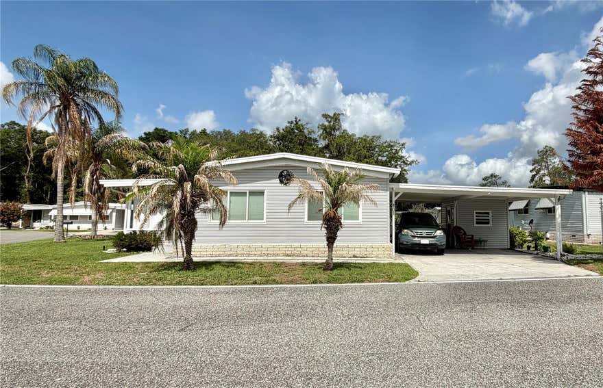 At last, the home you’ve been waiting for in Hawthorne at Leesburg! Situated on a premium corner lot, this beautifully maintained, tastefully furnished home offers fantastic lake views and exceptional value. Relax in the Florida room while enjoying peaceful water views and stunning sunsets from the comfort of your home. The spacious floor plan features a coastal-inspired primary suite with a walk-in closet and en-suite bath with a walk-in shower. A guest bedroom can easily serve as a home office or hobby room, and the guest bath includes a tub for added convenience. The fully equipped kitchen offers a cooktop, microwave, double oven, ample cabinetry, and generous workspace. An in-home laundry area with a full-sized washer and dryer adds everyday convenience, while beautiful window treatments provide warmth and charm throughout. Recent updates include upgraded windows (2010), durable exterior vinyl siding, a new roof (2015), and an HVAC system (2015), providing peace of mind for years to come. An extra-wide carport, desirable corner-lot location, and beautiful lake views complete this move-in-ready gem. Don’t miss this opportunity to enjoy comfort, convenience, and one of the most scenic settings in Hawthorne at Leesburg!.............Hawthorne at Leesburg is an active, resident owned, 55+ cooperative, waterfront, gated community, with beautifully landscaped grounds, lakes with illuminated fountains and a relaxing and comfortable gazebo. The affordable monthly maintenance fee of $397 includes water, sewer, lawn mowing, private emergency services and storage space for recreational vehicles, boats, trailers and much more! The beautiful clubhouse is complete with a full-time program coordinator, more than 100 different activities and seating for 550. It has a hospitality lounge, card rooms, craft rooms, billiard room, fitness center, library, fine arts room and many more. There is excellent fishing, outdoor geo-thermally heated pool and two enclosed therapeutic pools. Hawthorne boasts a private marina monitored by an electronic security system with over 120 boat slips and access to the Harris Chain of Lakes and beyond.