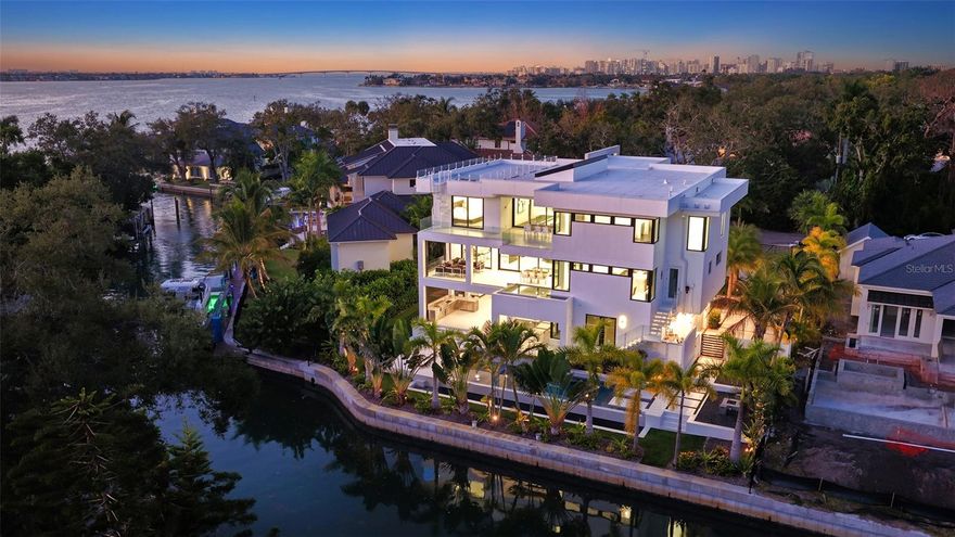 Stunning waterfront three story, coastal modern, single-family waterfront home is the perfect blend of comfort and luxury located in the treasured Cherokee Park neighborhood. Nestled on a street adorned with majestic oak and canopy trees, this exceptional property offers both privacy and grandeur. As you approach this generous lot, you'll be greeted by an electric gate entryway. Choose to park in either the detached two-car garage beneath the guest house or the hidden 6-8 car garage on the side of the house. The garage level features a private gym with a bathroom and an extraordinary outdoor living space that includes both covered and uncovered areas, a stainless steel outdoor kitchen, and a fire pit. Entering the home, you're captivated by a glass box foyer entryway with a custom staircase and state of the art glass elevator. There is also an entryway through the 6+ car garage leading to the elevator. The spacious second-floor living area boasts an open floor plan perfect for any event. The elegant great room features a custom glass floor and firebox, leading to a beautiful open kitchen with custom cabinets, waterfall stone countertops, and Subzero and Wolf appliances. Adjacent to the kitchen is a bonus room and an open yet private dining room, ideal for a wine collector with its floor-to-ceiling glass wine cellar that doubles as an art piece. Behind the kitchen cabinetry, you'll find a separate sizable pantry and laundry room. This floor also features a beautiful balcony accompanied by a glistening hot-tub/dipping pool that waterfalls into your main pool. Make your way to the third story to find 4 on suite bedrooms and a second laundry room. The primary bedroom offers an expansive layout that seamlessly blends comfort and elegance. The true highlight is the gorgeous balcony overlooking the pool that leads to a staircase up to the breathtaking rooftop. From here, you will enjoy panoramic views of the spectacular Sarasota. Whether you’re hosting a sunset soiree or savoring peaceful morning coffee, this rooftop oasis provides an extraordinary vantage point. This seamless indoor-outdoor flow and the captivating scenery make this property a true gem for those seeking both luxury and tranquility in a prime location.