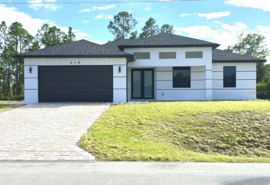 Modern elegance meets Florida living in this stunning 4 bedroom, 3 bathroom home in Lehigh Acres. From the striking curb appeal with a sleek black garage and paver driveway to the light-filled contemporary interior, this property is truly move-in ready. The open concept floor plan features a designer kitchen with high-gloss white cabinetry, stainless steel appliances, black quartz countertops, and a warm wood-accented island perfect for entertaining. Throughout the home, polished marble-look tile flooring adds a seamless, luxurious touch. Each bathroom showcases modern finishes with frameless glass showers, dual vanities, and elegant tile work. The thoughtful layout provides space and privacy for the whole family, while large windows and clean lines create an airy, inviting feel. Conveniently located near Fort Myers, shopping, dining, and outdoor recreation, this property combines style, comfort, and value in one exceptional package. Don’t miss the opportunity to own a brand-new, show-stopping home in a growing community—schedule your private tour today.