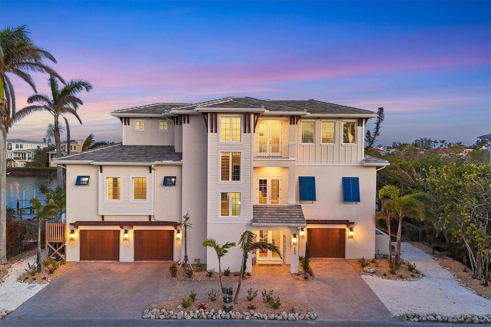 Along the tranquil shores of Gull Bayou, 608 Bayview Drive on Longboat Key offers an unparalleled blend of waterfront luxury and island living. With approximately 100 feet of direct water frontage, this exquisite home boasts breathtaking views of the bayou, where herons, ospreys and pelicans create a serene natural backdrop. A boater’s dream, the property provides easy access to the Intracoastal Waterway and the Gulf of Mexico with no fixed bridges, ideal for exploration and quiet enjoyment. Beyond its spectacular setting, this home’s thoughtfully designed interior balances sophistication and coastal comfort. A circular paver driveway leads to a covered entry, where French glass doors welcome you into an elegant foyer. The open-concept living space, complete with a seamless flow between the kitchen, dining and living areas, features a wall of sliding doors that extend to a screened-in terrace, offering panoramic views of the bayou and beyond. A private balcony, accessible via French doors, further enhances the indoor-outdoor living experience. The gourmet kitchen is outfitted with premium appliances, including a six-burner Wolf range, a Sub-Zero refrigerator and a Wolf warming drawer. White cabinetry, quartz countertops, a walk-in pantry with wood shelving, and a large central island with designer pendant lighting complete the space. An outdoor kitchen with an Artisan grill, granite countertops and a beverage cooler make alfresco dining effortless. The primary suite is a sanctuary, featuring terrace access, two custom walk-in closets and an en-suite bath with dual vanities, a private water closet and a spa-like walk-in shower. The guest level is equally inviting, offering two spacious bedrooms, two well-appointed baths and a bonus room with terrace access. A dedicated office, a stylishly equipped laundry room and a three-stop elevator add to the home’s functionality. Outside is a peaceful waterfront retreat, with dock and lift providing direct access to prime boating waters whether you prefer to paddle through the mangroves or venture out on a sunset cruise. The expansive pool deck surrounds the heated, saltwater pool and spa and provides numerous covered and uncovered living and dining spaces. Just steps from the beach, this Longboat Key residence is the ideal fusion of coastal elegance and relaxed island living.
