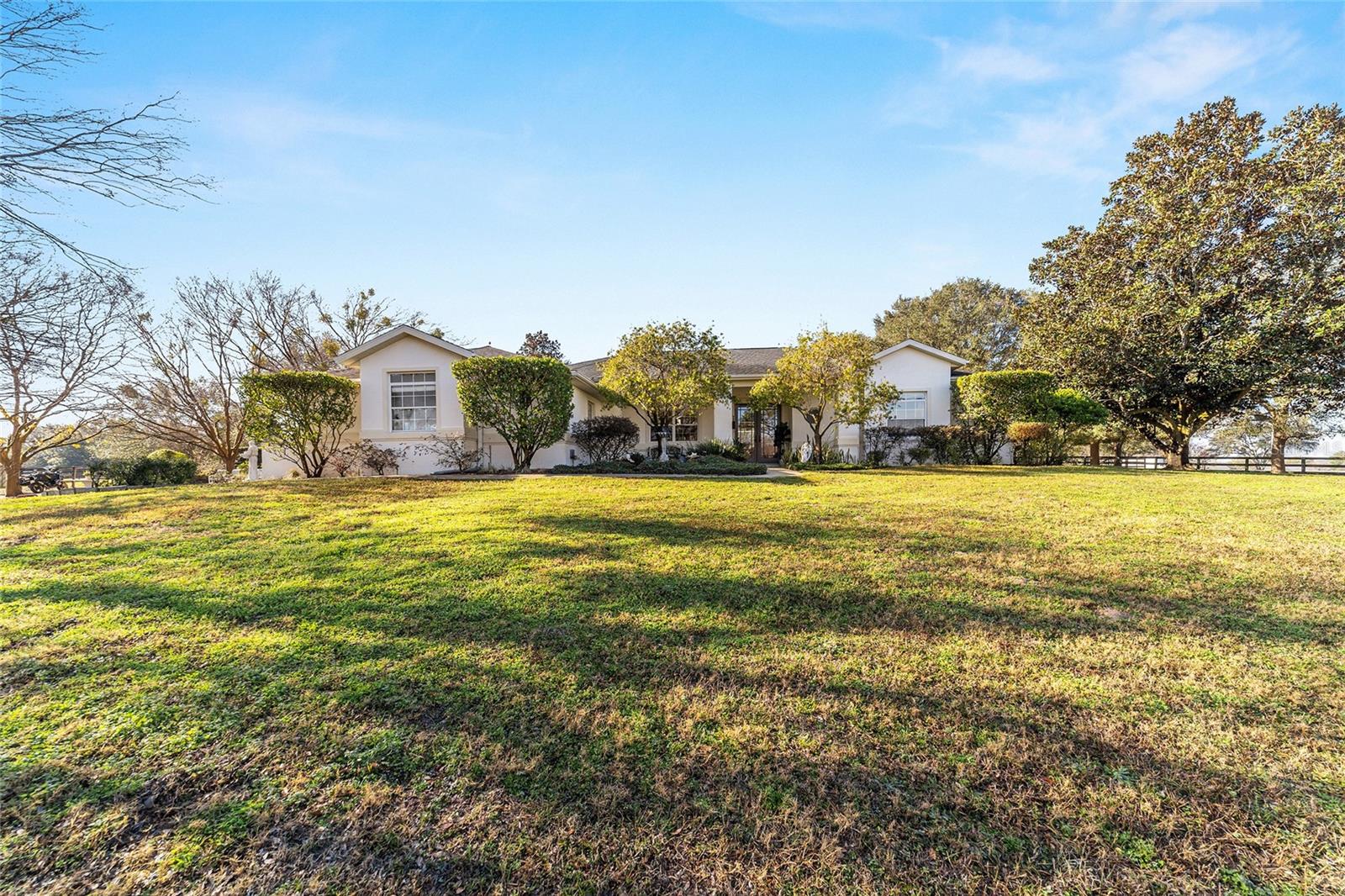 Nested among 25 acres of pristine countryside, this exceptional equestrian property offers everything the dedicated horse enthusiast could desire. The thoughtfully designed facility seamlessly blends luxury living with professional equestrian amenities, creating the perfect harmony of comfort and functionality. A total of 10 paddocks are in place, each featuring gentle shade from mature trees and automatic waterer for added ease of care. An additional round pen is also established, adding additional options for training. Two barns, both of which offers a concrete block construction and center aisle design, offers a combined total of 30 stalls with a feed room, tack room, fly spray system, and a large, covered wash rack area with multiple spaces. Both barns come with their own private barn apartments, which provide additional options for farm managers or seasonal rental opportunities. A larger two-story barn apartment is attached to the larger barn and includes a full kitchen, a large living/dining room combo, and upper loft with a large bedroom, full bathroom, and private balcony. The smaller barn includes an apartment with multiple bedrooms and a fully equipped eat-in kitchen, living room, and potential office space. For additional guest options, the property also features RV hookup and storage space. Surrounded by tasteful landscaping towards the back of the property is the main residence, which offers a total of 3-bedrooms and 2-baths and totals over 2,500 sq.ft. of space. Light and bright, the home features large windows to take advantage of the surrounding views, cathedral ceilings, and tile flooring throughout the main spaces. The kitchen is well appointed with ample cabinet and granite countertop, stainless steel appliances, additional pantry, and breakfast bar. The living room is incredibly inviting and spacious, directly open to the Florida Room which offers direct access to the pool area. While all bedrooms are comfortable, the primary suite is especially notable with a large layout, private access to the pool, two large walk-in closets, and a private en-suite with glass-door shower, garden tub, and dual vanities. Those who enjoy hosting will love the screen-enclosed pool area, which features an expansive pool deck with covered area for seating and gorgeous views of the back portion of the farm. This unique farm has a convenient location near US Route 301 and 441, making it a breeze to explore either Ocala or Gainesville. Don't miss this incredible opportunity to live your dream