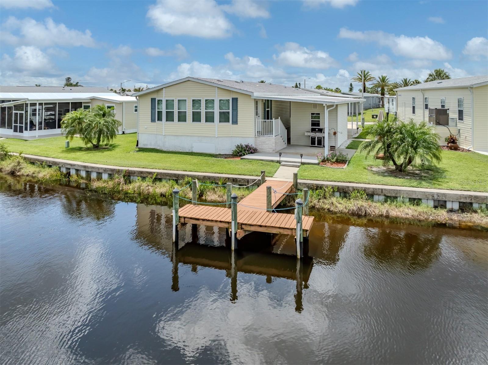 Welcome to this beautifully maintained 2008 manufactured home offering 1,700 sq ft of comfortable living space, situated directly on a tranquil canal with its own private dock in the highly sought-after 55+ waterfront community of Harbor Cove in North Port, Florida. This spacious 2 bedroom, 2 bathroom home features an expansive Florida/veranda room located at the rear of the home, fully under central air, with large windows that provide stunning canal views and fill the space with natural light.
The open-concept layout includes a generous living area with extra-wide hallways for easy accessibility. The kitchen is warm and inviting with hickory-colored cabinetry, abundant cupboard space, and two appliance garages, offering both charm and functionality. The oversized primary bedroom features a large walk-in closet and an ensuite bath with dual sinks. The guest bedroom also has a walk-in closet, and the laundry is conveniently located inside the home.
Recent updates include a shingle roof installed in 2022, a new AC system in 2021 with sanitized ducts and a 10-year warranty, and a hot water heater installed in 2017. For added stability, Intelli-jacks have been installed underneath the home to maintain a level foundation and ensure the tiedowns remain secure. Outside, enjoy a large covered patio in the back, a spacious shed with workbench, and all the essentials for Florida living. The home comes fully furnished and even includes a golf cart.
Harbor Cove is a vibrant 55+ resident-owned waterfront community with direct access to the Myakka River, Charlotte Harbor, and the Gulf of Mexico. Residents enjoy a full-service marina, boat ramp, kayak launch, two heated pools, hot tub, fitness center, tennis and pickleball courts, shuffleboard, and a clubhouse offering a wide variety of social activities and events. Pet ownership is restricted and permitted only in certain sections of the community with specific guidelines. Experience the Florida lifestyle in this move-in ready waterfront home.