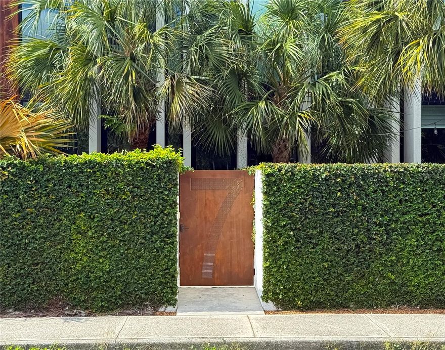 Discover your dream residence at RainGarden Condominiums in Downtown Winter Haven! Designed by renowned architect Max Strang, this stunning townhouse embodies a modern design within a tropical landscape that provides an atmosphere of serenity in the heart of a lively downtown. Prepare to be wowed by the blend of contemporary aesthetics and organic elements, transforming this two-bedroom, two-and-a-half-bathroom residence into a unique piece of architecture! This interior unit is one of nine townhomes that make up the RainGarden Condominium. Upon entering the secured gate into your private courtyard, you’ll immediately notice the lush landscaping and shady tree canopies that provide a peaceful place to relax or entertain guests. Step inside and enjoy a spacious and airy layout that effortlessly connects the living, dining, and kitchen areas. The large custom windows bathe the space in natural light, while the randomized, vertical fins on the front facade provide generous shading and privacy to the outside. The living room dazzles with 9'9" ceilings, elegant concrete floors, dining area, and expansive floor-to-ceiling windows. The gourmet kitchen features a breakfast bar, high-end GE appliances, granite countertops, and ample cabinet space, blending functionality with style. Access your second story via an integrated wooden stairway situated in a clerestory expanse that opens to a skylighted landing. Upstairs, the lofted master bedroom beckons with floor-to-ceiling windows, refined wood floors, an en-suite bathroom, and abundant closet space. The master bath features a double vanity, a large walk-in shower with elegant finishes, and a spacious walk-in closet. The second bedroom boasts a similar en-suite bathroom with a walk-in closet and plenty of storage. Enjoy the convenience of a second-floor washer and dryer as well as an ample storage closet. Located in the heart of Downtown Winter Haven, this home offers an urban lifestyle where you can “live, work, and play” all within a few blocks. You can leave your vehicles in the attached two-car garage and enjoy the vibrant neighborhood with new restaurants, coffee shops, retailers, and other entertainment just steps away. There are also additional visitor parking spots in the rear and ample street parking available on Ave A. This location cannot be beaten! Centrally located between Tampa & Orlando and within 1 1/2 hours of both east-coast and west-coast beaches. Or take your family out on the coveted Chain of Lakes where you can boat or swim between 22 different lakes! Don’t miss out on the opportunity to purchase this architectural gem! HOA provides for trash pickup, sewer, common electric and water expenses, exterior maintenance and landscaping.