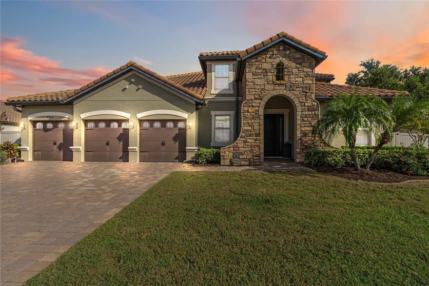 Experience refined living in this exquisite 5-bedroom, 4-bath residence, offering 3,739 square feet of thoughtfully designed space in the private gates of Brooks Cove. The home makes a striking first impression with its stone-accented façade and spacious 3-car garage. Inside, soaring ceilings and graceful archways open to a grand family and dining area, flowing seamlessly into the living room and gourmet kitchen. Designed for both everyday ease and elegant entertaining, the kitchen features a center island, granite countertops, breakfast bar, induction cooktop, stainless steel appliances, and a custom dry bar ideal for a coffee bar. The main level hosts four bedrooms, two baths, and a versatile flex room perfect for a home office, media space, or guest retreat. The primary suite is a true sanctuary with French doors to the poolside lanai and a spa-inspired bath boasting dual vanities, soaking tub, oversized walk-in shower, and an expansive closet. Upstairs, a loft, additional bedroom, and full bath provide even more room to relax or entertain. The backyard is a private oasis: a screened lanai with heated saltwater pool, hot tub, and abundant space for outdoor living. Modern upgrades include solar panels, new water and pool heating systems, triple-pane sliding patio doors, EV charger, and enhanced kitchen finishes. Conveniently located near premier shopping, dining, and major highways—with effortless access to downtown Orlando, the airport, and world-famous theme parks—this home perfectly blends luxury, comfort, and convenience.