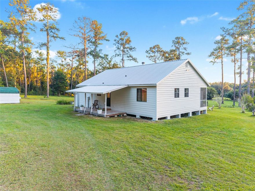 Tucked along a peaceful country road where deer and wild turkeys often wander, this charming 2 Bed/2 Bath farmhouse sits atop a gentle hill surrounded by 5 Acres of open pastures and endless skies. From sunrise to sunset, the panoramic views are nothing short of breathtaking — the perfect setting for anyone craving tranquility and wide-open space. It’s not uncommon to spot cattle and sheep grazing in the nearby fields, adding to the peaceful escape.

Recently refreshed with brand-new exterior paint, this home blends rustic character with thoughtful modern upgrades. The kitchen features a new microwave, updated plumbing, a stylish pendant light over the sink, and convenient pull-out cabinet drawers for easy organization. Enjoy the comfort of an on-demand water heater and the efficiency of Clay Electric utilities, well, and septic — keeping monthly costs low while maintaining modern convenience.

Inside, the spacious living area is anchored by a cozy wood-burning fireplace, perfect for cool Florida evenings. The primary suite offers a large walk-in closet and a beautifully updated bath, while the rest of the home features easy-care flooring throughout —No Carpet! 

Step outside to a screened-in back porch that overlooks rolling landscapes, ideal for morning coffee, golden-hour sunsets, or simply soaking in the tranquil surroundings. The property is as functional as it is beautiful, with two carports (one with a concrete floor and attached workshop), a fire pit area, and a private electric and solar-powered entry gate shared with one neighbor.

For those who love to garden or grow their own food, the property includes a mini orchard with Persian lime, Key lime, tangerine, Bearss lemon, and calamondin trees, as well as banana trees and blueberry bushes — your own backyard harvest ready to enjoy.

Practical updates include a New AC installed in 2022 and New Metal Roof- 2013, giving peace of mind for years to come. Nestled between Gainesville and Alachua, this hilltop retreat offers the best of both worlds: the quiet of country living with the convenience of town just minutes away.