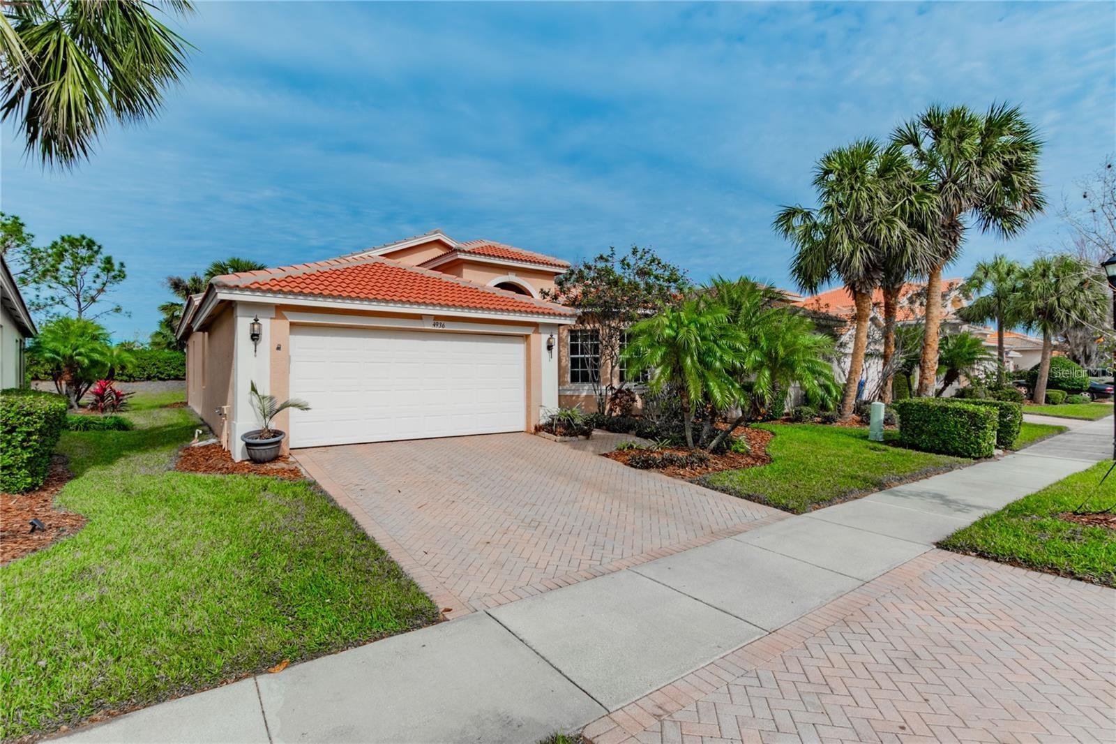 One or more photo(s) has been virtually staged. Luxury Living in Valencia Lakes. Welcome to this beautifully designed Florence model home located in Valencia Lakes, Tampa Bay’s premier 55+ community offering the perfect blend of luxury, comfort, and resort-style living. This exceptional residence features three spacious bedrooms, two full bathrooms, and a two-car garage, all thoughtfully designed with high-end finishes and elegant touches throughout. As you enter through the grand foyer, you're greeted by a soaring 13-foot coffered ceiling, classic crown molding, and engineered hardwood flooring that flows seamlessly through the entire home. In the wet areas, durable 17x17 tile flooring adds both practicality and charm. With no carpet in the home, you’ll enjoy a cleaner, more allergy-friendly environment. The expansive great room is the heart of the home, showcasing a custom built-in wall unit with an electric fireplace and oversized triple glass sliders that open onto a spacious rear lanai—an ideal space for entertaining or simply enjoying the Florida breeze. The adjacent informal dining area features elegant trim work and custom wall mirrors, creating a refined and inviting ambiance for meals and gatherings. The gourmet kitchen is a chef’s dream, offering granite countertops, 42-inch raised-panel white cabinets, a stunning tumble stone marble backsplash, and a convenient menu desk. A porcelain undermount sink is paired with a reverse osmosis water filtration system, while upgraded stainless steel appliances and a bright breakfast bay window complete the space with both style and functionality. The primary suite serves as a peaceful retreat, offering two walk-in closets, a coffered ceiling, and direct access to the lanai through triple sliding doors. The luxurious en-suite bathroom includes dual granite vanities with designer mirrors, a Roman soaking tub, and a large frameless glass-enclosed shower with a tiled seat. Designed with privacy in mind, this home features a true split-bedroom layout. The two secondary bedrooms are located away from the primary suite, perfect for guests or a home office. The second bathroom includes a tub and shower combination with a shampoo niche, granite countertops with a banjo top for additional counter space, and a custom mirror with a built-in medicine cabinet for extra storage. The well-appointed laundry room comes complete with a washer, dryer, utility sink, and cabinetry for added convenience. Additional upgrades include ceiling fans, stylish light fixtures, window blinds throughout, and a whole-home water softener system installed in 2023. The home also boasts a high-efficiency HVAC system with UV light and a new thermostat installed in 2016, a water heater replaced in 2018, epoxy-coated garage flooring, and a screened front entryway for added curb appeal. This home is located in the highly desirable Valencia Lakes community, known for its incredible lifestyle amenities. Residents enjoy a 40,000-square-foot clubhouse, resort-style pools, tennis and pickleball courts, fitness classes, an on-site bistro, an art studio, clubs, live entertainment, and so much more. Whether you’re seeking a vibrant social atmosphere or a peaceful retreat, this home offers the best of both worlds. Contact us today to schedule your private showing and experience the exceptional living that Valencia Lakes has to offer.
