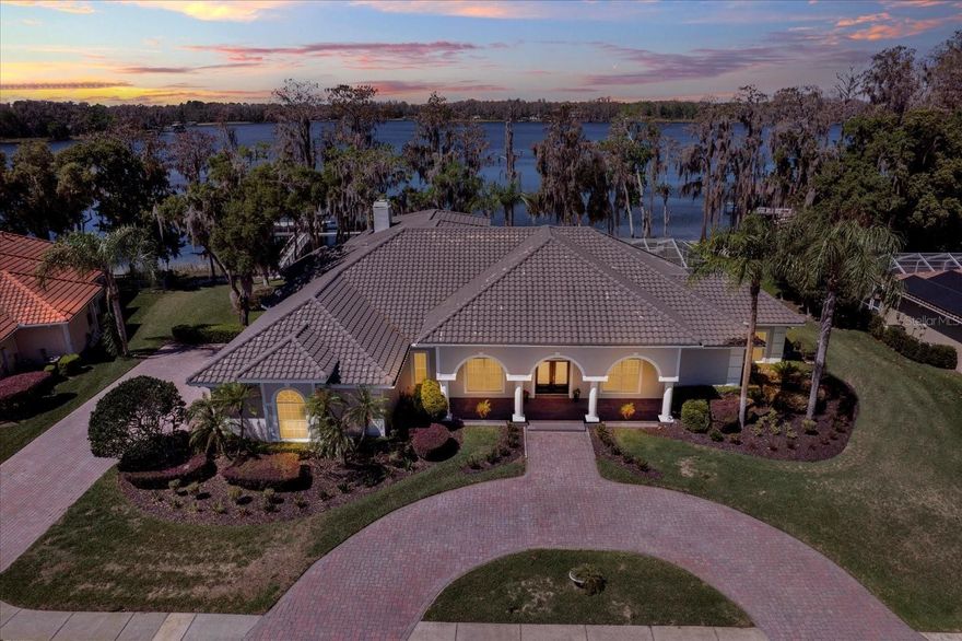 If you're looking for breathtaking sunsets and gorgeous lake scenery, look no further. Tucked into the back of a gated community, the Preserve at Lake Thomas, this remarkable home offers the perfect blend of privacy and natural beauty. With almost 180' of frontage on Lake Thomas, the panorama will not disappoint. The private dock includes two lifts, shaded seating, and even ladders to get in and out of the crystal clear spring-fed lake. Imagine spending your mornings sipping coffee on the dock, watching herons glide across the glassy water, or spending your afternoons carving across the lake on skis with friends. As the day winds down, the sandy beach and lakeside seating area become the perfect spot to soak up one of those legendary Florida sunsets. Arriving at the home, you're greeted by a grand circular driveway and a side-entry three-car garage, setting the tone for the elegance that awaits inside. The double door entryway opens into a bright, open dining and living room, where patio doors frame a stunning view of the lake beyond. To the right is a spacious office with floor-to-ceiling built-in bookshelves, a full pool bath, and the primary suite. From the primary bedroom, you'll wake up to breathtaking views of the pool and lake. The primary bathroom includes lots of natural light, expansive counter space, a jetted tub, and an oversized shower. To the left of the entryway is the open kitchen with breakfast space and snack bar, along with the family room, three bedrooms, and access to the open loft. The family room has open views of the lake, a fireplace, a built-in TV console, and sliding patio doors leading to the pool. At the back of the house is a generously sized bedroom, again framing gorgeous scenery of the lake, and a full bathroom. This area has a pocket slider and would serve wonderfully as an in-law suite. The other two bedrooms share a Jack and Jill bathroom, and both have walk-in closets and a bay window. Just off the kitchen, the spacious laundry room has a large closet, generous cabinet storage, and ample counter space. Upstairs, the large loft overlooking the family room includes a wet bar and even more lake views to enjoy. Outside, owners will take in the expansive screened pool area with a spillover heated spa and shaded areas for relaxing throughout the day. The grounds have been well thought out with a walking path to a seating area to soak up the sunsets and a sandy beach. This home encompasses two lots to enjoy the best scenery and privacy on this 165-acre ski lake.
