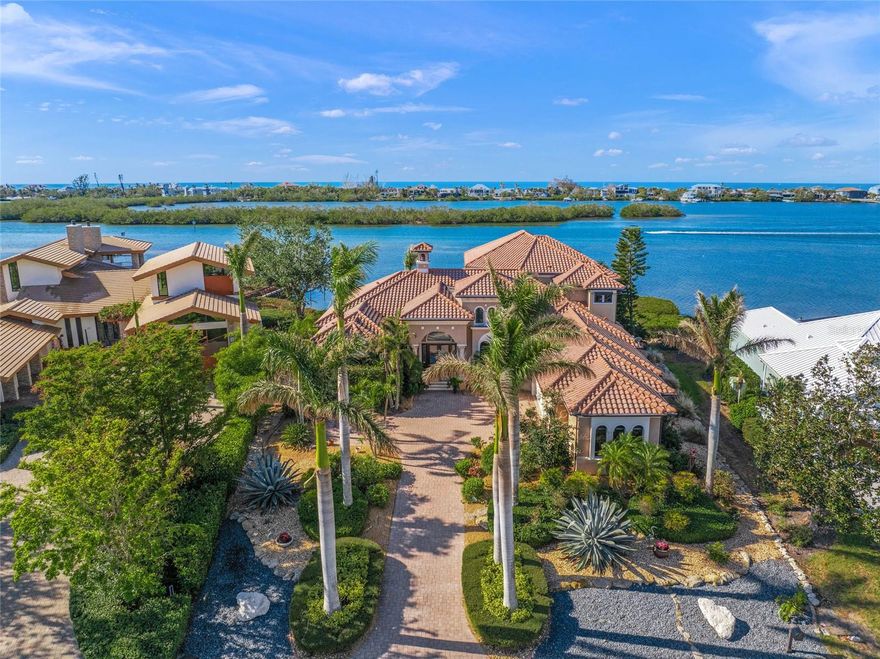 This stunning waterfront residence in Southbay Yacht and Racquet Club is a gem on Florida’s Gulf Coast where boats are accommodated in a deep-water marina for low fees. Boasting over 135 feet of water frontage and surrounded by lush tropical landscaping and majestic Royal Palms. Its refined curb appeal sets it apart as a one-of-a-kind property. The custom John Cannon home features a grand double door entry that opens to breathtaking wide open bay views. Inside, the home showcases high-end finishes and upgrades, including impressive, vaulted ceilings reaching up to 21 feet. You'll find abundant crown molding, elaborate tray ceilings, and exquisite wall finishes adorned with artfully painted faux designs and plantation shutters throughout. The home is designed for entertaining, with a full bar and wine room for guests, as well as an upper-level wet bar. The chef's kitchen is a culinary dream, featuring a spacious granite island, a gas cooktop with a pot filler, and views overlooking the pool, patio and bay. An upper-level bonus room offers versatile space for play, music, movies or exercise, all while enjoying some of the best views in the house. The main level primary suite is a serene retreat with a sitting area, two large closets and a luxurious bath that includes a garden shower, large tub, dual sinks, and a separate toilet and bidet. The expansive outdoor living spaces, including main level and upper terraces, are ideal for enjoying sunsets and observing local wildlife such as ospreys, dolphins, manatees and a parade of boats. Private dock for sunset viewing and fishing. Ideally between Sarasota and Venice, this residence is just minutes from the pristine sands of Siesta Key and Nokomis Beach. Convenience abounds with nearby shopping, dining the Legacy Trail, private and commercial airports, and top-rated schools, including the renowned Pine View School. This exquisite home embodies the essence of Florida living. Southbay Yacht & Racquet Club lives up to its name with a newly renovated community clubhouse, geothermal pool, gym overlooking the marina, banquet rooms, three tennis courts, four pickleball courts, a bocce ball court, two shuffleboards, basketball, kayak storage area, a waterfront park, 20 acres of common grounds and miles of trails. Ideally in between culturally rich Sarasota and charming Venice, minutes to beaches, Legacy Trail, No. 1 rated Pine View School, shopping, waterfront restaurants and Oscar Scherer State Park. Walk to your boat or take your golf cart around the neighborhood. For those who seek an exceptional waterfront life, nothing compares.