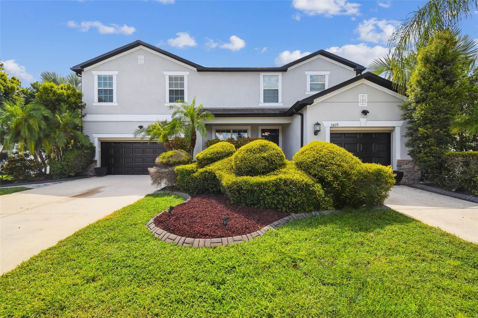 Located in the highly sought-after, A-rated Sunlake School District, this exceptional Washington model by Lennar offers nearly 4,000 sq ft of thoughtfully designed and fully livable space, including converted garage flex areas—featuring 4 true bedrooms (each with its own ensuite bathroom), 4.5 total baths, an upstairs loft, and a commercial-grade media room—all designed for luxury, comfort, and flexibility. Two split garages have been finished as livable flex spaces with 2022 mini-split ACs, insulated doors, smart locks, roll-down Phantom screens, upgraded lighting, and weatherproof flooring. Triple sliders lead to a vaulted 1,000 sq ft screened lanai with ceiling fans, quad outlets, and dedicated hot tub wiring, all surrounded by mature landscaping, decorative concrete walkways, and a fenced backyard with firepit seating and smart irrigation. Rich custom millwork, crown molding throughout, two French pocket doors, and dramatic wood-paneled feature walls set the tone, while the formal living and dining rooms offer a classic touch just off the entry. The gourmet kitchen is equipped with granite countertops, solid wood 36" upper cabinets, 2022 stainless steel appliances, a kitchen island, and a sunlit breakfast nook—and it overlooks the expansive family room with soaring ceilings, recessed lighting, and a Twin Star ceiling fan. The downstairs bedroom includes an ensuite bath and exterior access to the lanai—ideal for guests or multi-generational living. Upstairs, the expansive primary suite features two custom walk-in closets, a soaking tub connected to a glass and metal-framed shower, dual granite vanities, and a large linen closet for added storage and convenience. The additional bedrooms upstairs also include ensuite baths, ceiling fans, and are generously sized to provide comfort and privacy for family or guests. A versatile loft offers extra space for a gym, office, or playroom, and the professionally built media room includes a raised floor, Sony 4K projector, 130” screen, Bose 7.2 surround sound, and six reclining cinema chairs—formerly two bedrooms and easily converted back. Major upgrades include two new high-efficiency central AC systems (2022) with UV pathogen defense, solar hybrid water heater (2025), whole-house generator with dual propane tanks, surge protection, iron and heavy metal filtration system, water softener, recessed LED lighting, newer appliances, French drains, and full exterior paint (2025). Exterior enhancements include new dual sliders, smart-entry doors, and 8 HD security cameras with smart automation. Located in Wellington, a premier subdivision of Concord Station, this home is directly across from the amenity center and clubhouse. Concord Station offers resort-style amenities including a community pool with splash pad, clubhouse, fitness center, tennis and basketball courts, and playgrounds. Enjoy a private, upscale lifestyle with key destinations just minutes away: Publix at The Shoppes at Sunlake Centre, Sunlake High School, and Imagine School K–8 (3 mins), EOS Fitness, Chick-fil-A, Aldi, and Fresh Kitchen (5 mins), AdventHealth ER and Veterans Expressway (8 mins), TPC Tampa Bay (12 mins), Tampa Premium Outlets (15 mins), USF (22 mins), Tampa International Airport (25 mins), and Downtown Tampa (26 mins). Don’t wait—schedule your private showing today!