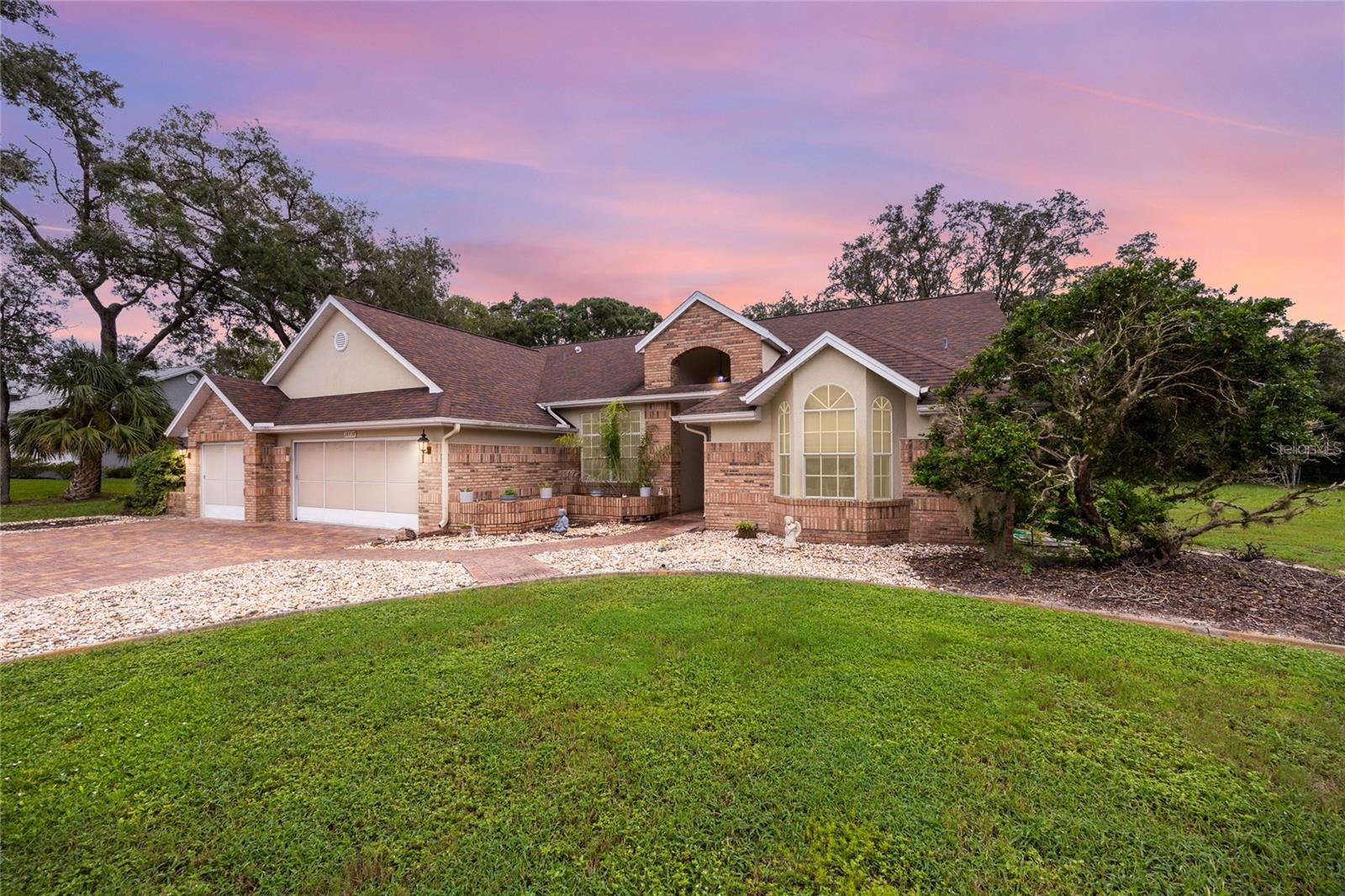 Make sure to check out the Virtual Tour for a 3D Model w/ Walkthrough, Floor Plan w/ Measurements, Video, & more! 18739 Bascomb Lane offers more than just square footage, it's a home that knows how to live large and entertain with ease. Inside its 2,527 square feet (with a whopping 3,661 square feet under roof), on .59 acres, you'll find this home has a thoughtful layout that gives everyone room to breathe with 4 Bedrooms, 3 bathrooms, a 3-car screened garage. From the moment you arrive, the wide brick-paver driveway sets the tone, framed by mature trees and a well-kept landscape that makes the exterior shine. The home's blend of brick and stucco, arched windows, and thoughtful details create curb appeal that feels both elegant and inviting. Inside, soaring ceilings and large windows flood the home with natural light. A generous kitchen anchors the heart of the home, complete with ample cabinetry, sprawling Corian counters, and a breakfast bar that opens to the family room and casual dining area. A separate formal dining room and living room provide plenty of options for entertaining or cozying up to the fireplace to read your favorite book. This Master Suite is a show stopper, with a sitting area, and private access to the patio, it has the 1st wing of the home all to itself. Making your way to your master bathroom with dual walk-in closets, a spa-style bath with soaking tub and walk-in shower, dual vanities to spread out. You will find 2 generous sized bedrooms and 1 bathroom in Wing 2, and the 4th Bedroom and bathroom across the hall (with back porch access) in the 3rd Wing. Step outside, and the back of the home opens to an expansive L-shaped screened patio with 5 separate access doors, including one from a bathroom for convenience. With ceiling fans, a wet bar, and room for both dining and lounging, it's an outdoor living space ready for morning coffee, evening gatherings, or simply watching the sandhill cranes wander by. Life in Autumn Oaks is about more than just your home, it's about the community. Wide, tree-lined streets w/ sidewalks make walking or biking a pleasure, while the active HOA keeps the neighborhood lively with regular events. Amenities include bocce, pickleball, basketball, a playground, grilling area w/ restrooms... with all these amenities, you can't help but become friends with neighbors. All with No CDD, No Flood Insurance Required, and a super low HOA at only 35.83/month! When it's time to explore beyond your neighborhood, you're just 15 minutes to Hudson Beach for waterfront dining and sunsets, 20 minutes from Weeki Wachee Springs for kayaking and mermaids, and under an hour from Tampa International Airport. Daily shopping, dining, and family-run businesses are close by, adding a welcoming small-town feel with big town conveniences. Homes like this one don't last long, set up your showing today!