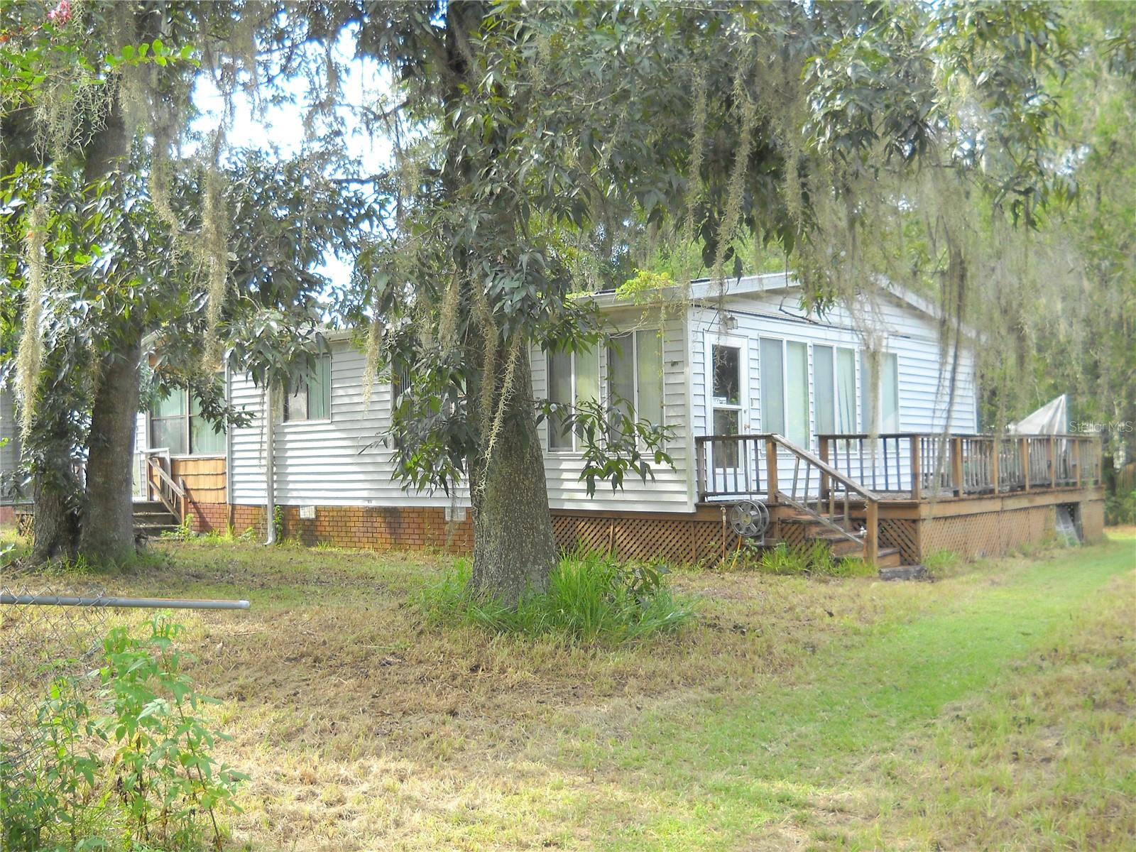Lovely home needs a little TLC. Was vacant for 3 years. The rooms are nice size, comfortable floor plan. the living area has a gas fireplace with built in shelves. On the side of the home is a long deck that opens to a 8 x 16 bonus room. Fruit trees, magnolias and crape myrtles. Thel large shed has electric, garage, workshop an carport. Area close to 301,441, 75, Ocala National Forest, Orange lake and Lake Lookloosa close by.. Short dead end road. This is an AS IS sale.