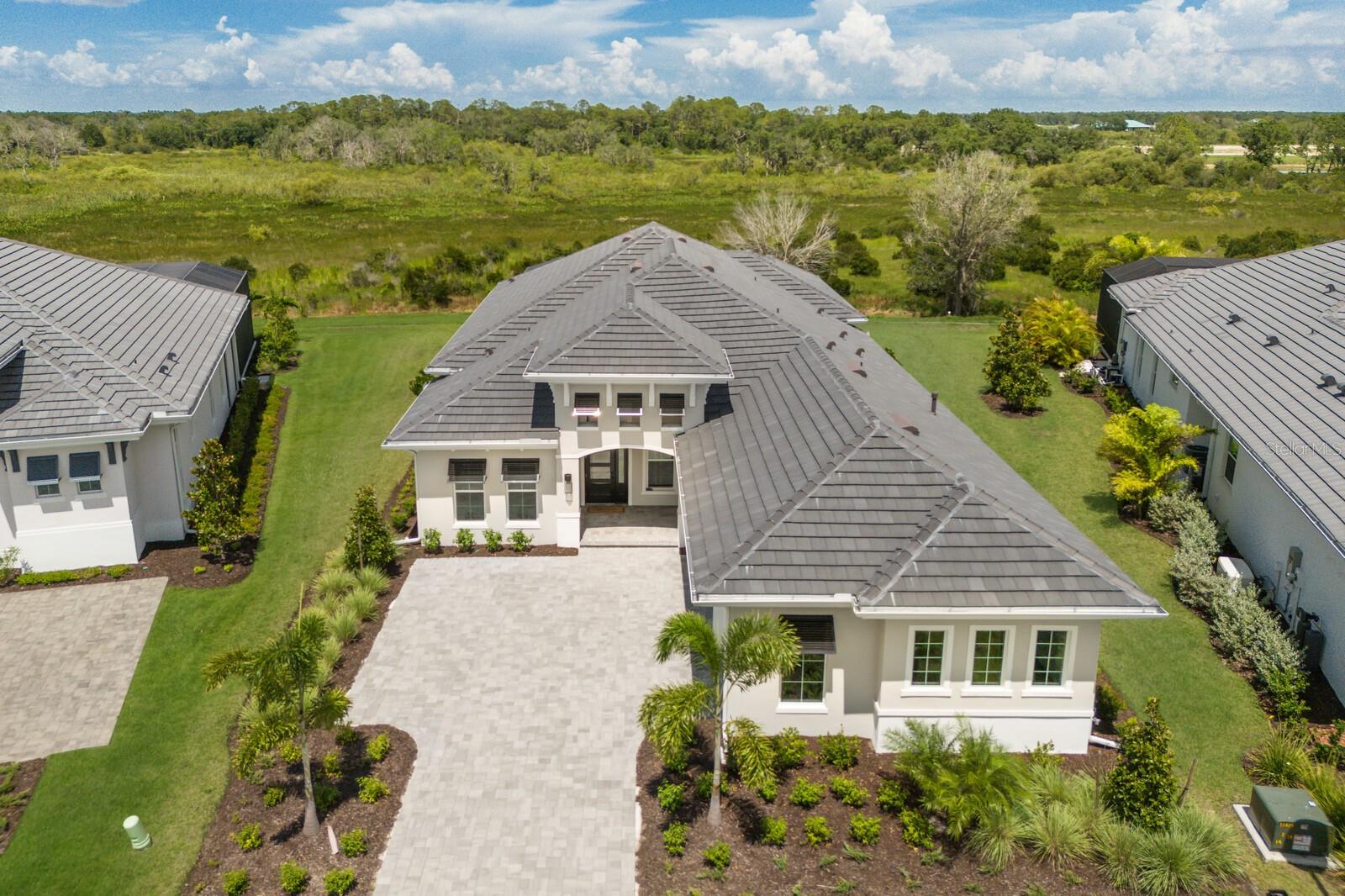New construction, PRICED LOWER THAN THE BUILDER! Ready now - and the LARGEST LOT available on the street and can be FENCED! This brand-new, never-lived-in luxury home seamlessly blends style and convenience. Situated on an OVERSIZED LOT in the BEST flood zone (Zone X), this Stock Luxury Home offers over 3,000 sq. ft. of living space, featuring PGT IMPACT RESISTANT windows AND sliding doors, 4 bedrooms, 3.5 bathrooms, a formal dining room, and a dedicated office/den. This exceptional home combines superior craftsmanship, sophisticated design, and the best of Florida living, while including features such as a spacious 3-car garage with epoxy flooring. Inside, the open-concept floor plan impresses with soaring ceilings, elegant lighting, and gorgeous engineered hardwood flooring that flows throughout the home. The chef-inspired kitchen is equipped with custom soft-close cabinetry, quartz countertops, a striking tile backsplash, a large island, and top-tier KitchenAid appliances, including a natural gas cooktop. The great room is ideal for entertaining, with a dry bar and 10' pocket sliding doors that completely open to the lanai for easy indoor/outdoor entertaining. Step outside to your own backyard paradise, complete with an expansive covered lanai, state-of-the-art outdoor kitchen, and a clear-view pool screen framing peaceful, unobstructed, greenbelt/preserve views that are tranquil and peaceful. The saltwater pool and spa are perfect for relaxing and enjoying the serene surroundings while having the privacy of extra space between homes. Wild Blue is Lakewood Ranch’s most desirable new community with an amazing location. Take a stroll just across from the community to the Sarasota Polo Fields! The community will feature a 25,000 sq. ft. resort-style clubhouse with a fitness studio, golf simulator, indoor and outdoor dining, and a theater. Residents will also enjoy access to the Midway Sports Complex (open now) with tennis & pickleball courts, a basketball court, kayak launch, walking trails, dog parks, and more. Located near Waterside shopping, dining, UTC shopping area/mall, Lakewood Ranch Main Street, and just a short drive to Sarasota Airport and the world-renowned Gulf Coast beaches, this home truly has it all.
