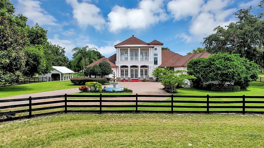 Experience timeless elegance and southern charm in this exquisite, one of a kind 9.66 acre estate, where every detail has been thoughtfully designed & engineered for comfort, beauty, and sophistication. Beyond the gated entrance, a grand paver driveway lined with magnolia trees leads to this stunning, custom 2-story home. This remarkable home showcases beautiful hand-scraped hickory floors with walnut inlays, soaring 12’ ceilings, 8' alder doors, plantation shutters, custom leather Nook ceiling, custom solar shades, and custom lighting & fans throughout. Exquisite millwork includes octagon columns encasing the Nook, 9” crown molding, and 7” baseboards. Glass-Craft mahogany double door entrance with 2 sets of stationary French doors welcomes you to the impressive Great Room with a decorative beam ceiling and double French doors leading out to the relaxing rear porch and wonderful pool oasis. The gourmet island Kitchen features granite counters, custom cabinetry, and a large walk-in storage pantry with room for wine storage. Charming breakfast Nook features a leather ceiling, bay window with views of the Viking Summer Kitchen, pool and the impressive gardens. You’ll love the formal Dining Room, which offers plenty of space to entertain friends & family on all sorts of special occasions. Magnificent & spacious Primary Suite encompasses a beautiful coffered ceiling, large walk-in closet, French doors leading to the rear porch and tranquil views. The luxurious en-suite boasts split vanities, 3 sinks, gorgeous travertine floor, large walk-thru shower, and an inviting free-standing platform tub. Climb the divine staircase up to the Family/Media Room highlighting a custom entertainment center, surround sound speakers, gas fireplace with Eldorado Stone, a Library/Craft Room, a half Bath, and front and rear porch balconies offering majestic sunrises & sunsets. The Family/Media Room also has a hidden attic access behind the book shelf. Enjoy the spacious Laundry Room which includes Washer & Dryer, granite counters and numerous cabinets. The 18 x 45 pool is nestled in surrounded by lush flowering plants & shrubs and features solar lights, 4 water jets, and soothing waterfalls. Even a private Pool House/Vanity Room is just steps away from the pool. You will love the Summer Kitchen featuring Viking appliances, Sedna granite counters, tongue & groove ceiling, and plenty of room to seat your guests at the bar. The oversized 3-Car Garage features an additional 20’ x 9’ workshop to keep all your tools & toys neatly stored, as well as a Generac generator. This amazing property includes a 10 x 16 storage shed, banana trees & a citrus tree too! A horse lover's dream with a 58 x 36 Main Barn complete with etched flooring, hay storage, 4- 12 x 12 stalls with Dutch doors to paddocks, fans & water supply in each stall, plus a 24 x 12 stall for foaling or equipment storage. The Tack Room/Barn Office features brick flooring, tongue & groove ceiling, cedar beams, cabinets, and a butcher block table. The Second Barn is 22 x 44 and offers 2- 12 x 12 stalls w/ fans, water supply, European style gates & partition walls, tongue & groove Tack Room/Barn Office, hay storage, and let's not forget the 4 chandeliers. Painted four-board fencing surrounds the entire property w/ gates between paddocks. This gorgeous Southern Plantation style home and horse property is truly “one of a kind” and ready for you to discover all it has to offer to begin your own fabulous memories.