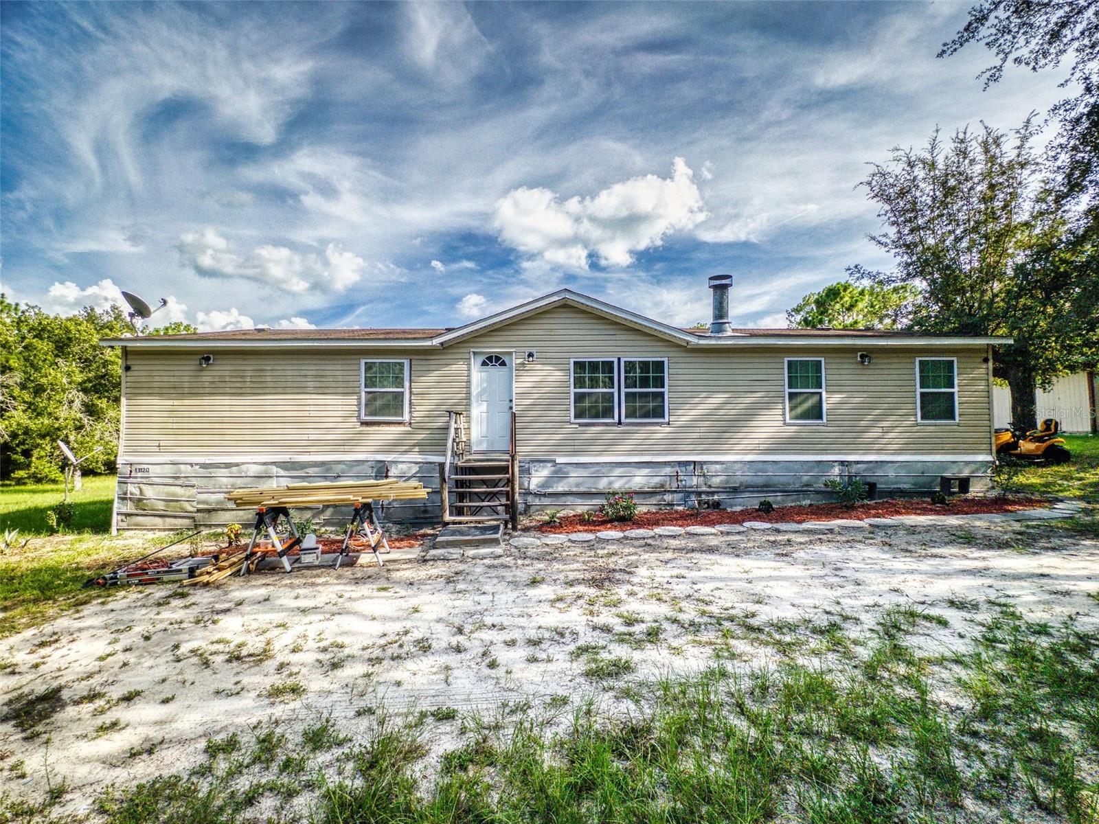 Rural privacy meets versatile outdoor living in Dunnellon, Florida. Situated on over two beautifully cleared acres, 13120 SW 90th Street delivers the ideal combination of space, functionality, and charm. The A1-zoned property rests quietly off a dirt road, framed by cathedral ceilings, engineered hardwood flooring, and an open-concept layout designed to maximize comfort and flow. Inside, the home features four spacious bedrooms and two full baths. The thoughtfully designed split-bedroom plan places the primary suite on its own wing for added privacy. This private en-suite includes walk-in closets and a bright, modern bath, walk-in shower with glass doors, a dual vanity and lot's of space offering a quiet refuge from the day. Schedule a private showing! At the heart of the home lies a beautifully remodeled kitchen, highlighted by solid-surface counters, a custom cooking island with bar seating, and sleek stainless steel appliances—including a high-end oven and refrigerator. With natural light pouring in from multiple angles, the entire space boasts a crisp, modern aesthetic that’s as functional as it is inviting. One of the standout features of this property is the over 1,000 feet of newly constructed, incredibly sturdy wraparound deck—perfect for everything from entertaining to outdoor expansion. An above-ground pool adds to the appeal, along with sliding glass doors that open the living space to the outdoors. Also there additional space that is enclosed to the rear of the home awaiting the finishing touches. With no HOA, well and septic systems in place, and ample room for pets, hobbies, or future additions, this home offers freedom and expansion to grow. Just minutes from Dunnellon and Ocala’s amenities, it's a great opportunity to enjoy acreage, privacy, and the peace of rural living in a thoughtfully upgraded residence. Schedule a private showing!