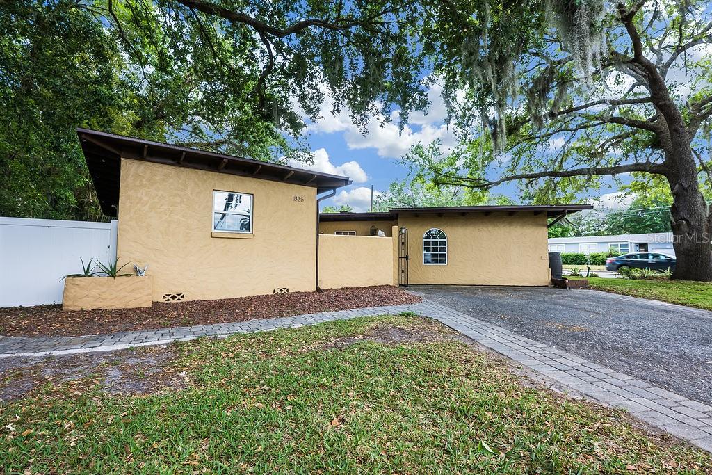 Welcome to Lake Sue Park in Orlando’s sought after 32803 – where character, charm and space come together seamlessly in one perfect home! This single story 4-bedroom, 2-full and 1-half bath layout sits on an expansive .37 ACRE DOUBLE LOT surrounded by mature oak trees, delivering the rare combination of privacy, beauty, and convenience. Located just minutes from Downtown Orlando, Audubon park, Mead Gardens, Beeman Park, and TOP-RATED SCHOOLS, it is the kind of setting that balances quiet dead end streets with easy access to everything the city has to offer. Stepping inside you will find FLOOR TO CEILING WINDOWS that flood the living spaces with NATURAL LIGHT, formal living and dining rooms that are filled with warmth, while a raised casual living space and exposed WOOD BEAM CEILINGS add even more character. Designer WOOD LOOK TILE FLOORS and SMART LIGHTING bring a modern touch while still honoring the home’s timeless charm. The UPDATED KITCHEN is a showpiece, complete with rich cabinetry topped with crown molding, desirable STAINLESS STEEL APPLIANCES, complementary backsplash, a central ISLAND with bar seating, and generous counter space. The huge BONUS/MEDIA ROOM offers endless flexibility – easily converting to a 4th bedroom, home theater, studio or game room. A wet bar just outside makes entertaining effortless, while a large laundry room and second flex space provide options for an office, craft room or extra storage. The unique layout was designed with privacy in mind putting the PRIMARY SUITE on its own wing - completely separate from the other bedrooms. Bedrooms two and three are tucked away on the other side of the home with a shared full bath between them, creating a functional SPLIT BEDROOM plan. Outside, the living space expands with multiple patio areas, a VINYL PRIVACY FENCE, and a massive backyard – plenty of room to relax, garden, gather or add the pool you have always wanted. PRIVATE LAKE ACCESS delivers even more outdoor enjoyment, whether you prefer kayaking, fishing, or simply taking in the view. Also noteworthy – the UPDATED ROOF, NEWER A/C UNITS, 3 SMART NEST THERMOSTATS, fiber internet available in the community, and with NO HOA you will have the freedom to truly make the property your own. Perfectly situated on a large CORNER LOT shaded by stately oaks, this home offers something you don’t find often – whether you are drawn in by the light filled interiors, double lot, or the unbeatable location, this Lake Sue Park gem is ready to welcome its next chapter as your new HOME SWEET HOME!