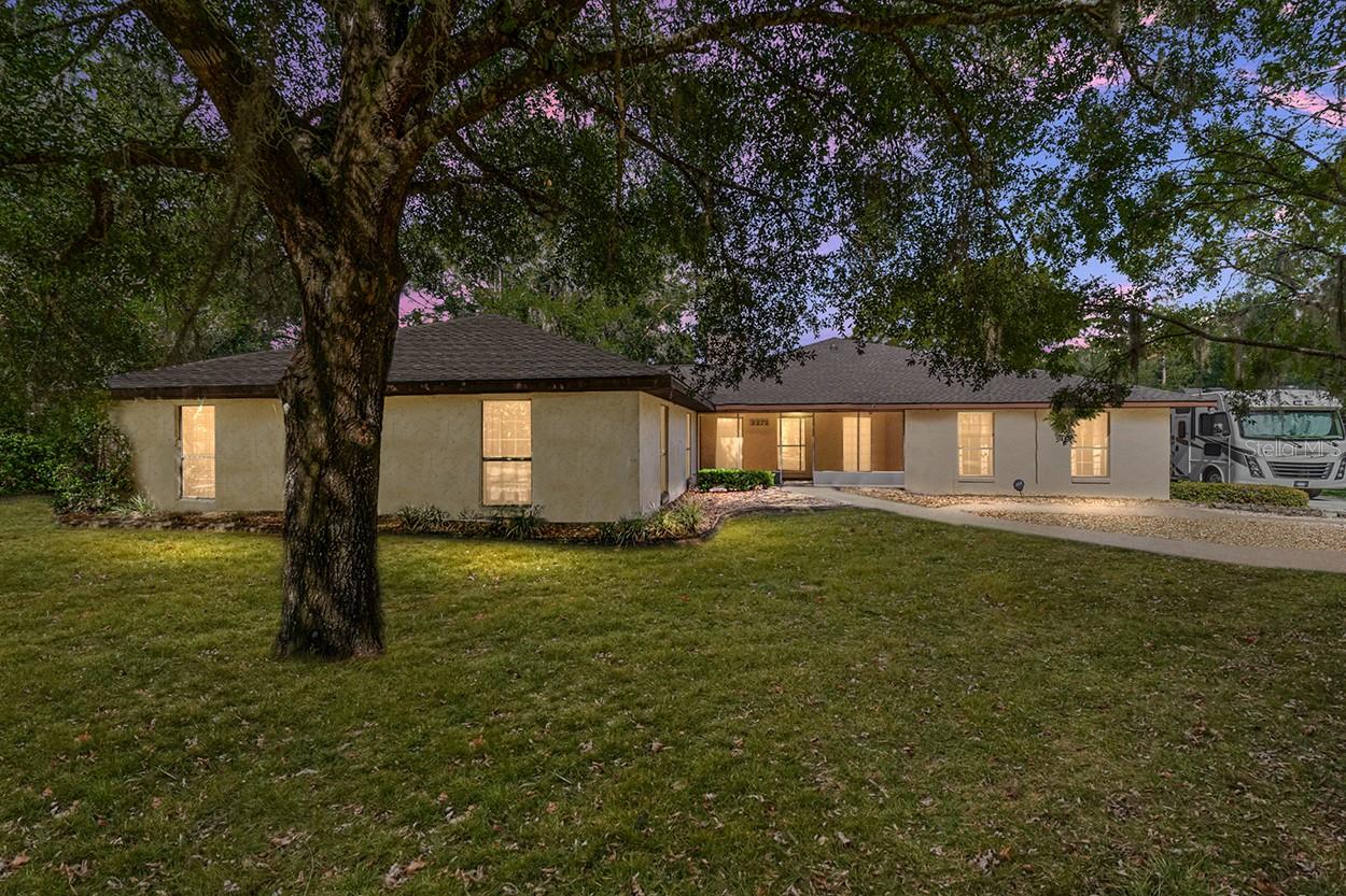 Welcome to this charming and spacious home, nestled on a sprawling 3.019-acre lot with a private, wooded feel. Built in 1983 with a significant addition in 1999-2000, this 3,254 sq. ft. residence offers a unique blend of classic features and modern convenience. Upon entering, you'll be greeted by a lovely foyer with a full wall of built-in wood cabinets, providing ample storage. The living room is anchored by a stunning, wood-burning stone fireplace and features a ceiling fan for comfort. The kitchen boasts a classic charm with its tan counters and wood cabinetry. It is equipped with a stainless-steel refrigerator, dishwasher, and range. A small island and a charming eat-in area with bay windows and a fan complete the space. The addition is a standout feature, offering a massive great room with a vaulted ceiling and two ceiling fans. Wraparound windows flood the room with natural light, and double doors lead out to a screened-in lanai with a fan and a covered area, perfect for outdoor living. The home features 3 bedrooms, each with a ceiling fan. The primary suite includes a double closet, while the ensuite bath offers a step-in shower, a single sink, and a vaulted overhead cabinet. The 2nd bathroom has a tiled tub/shower, a large single sink, and a skylight. A 3rd bathroom features a sink and a tiled shower. A unique feature of this home is the mother-in-law suite. This suite includes a living room with carpet, a mini-kitchen with an oven, a mini-refrigerator, and upper and lower cabinets. It also has a bedroom with a fan, a half bath with a toilet, and its own door to the garage. Additional highlights include a dining room currently set up as an office with two fans and wraparound windows. The HVAC system is approximately 5-6 years old. A screened front porch adds to the curb appeal. The home also features a 3-car garage with a washer/dryer hookup, built-in cabinets, and a wood shed. The interior was freshly painted approximately 2 years ago, and a new roof was recently installed. With its expansive acreage, this property offers a peaceful, wooded setting with approximately an acre of woods on either side, ensuring privacy and tranquility. Don't miss the opportunity to own this spacious and versatile home!
