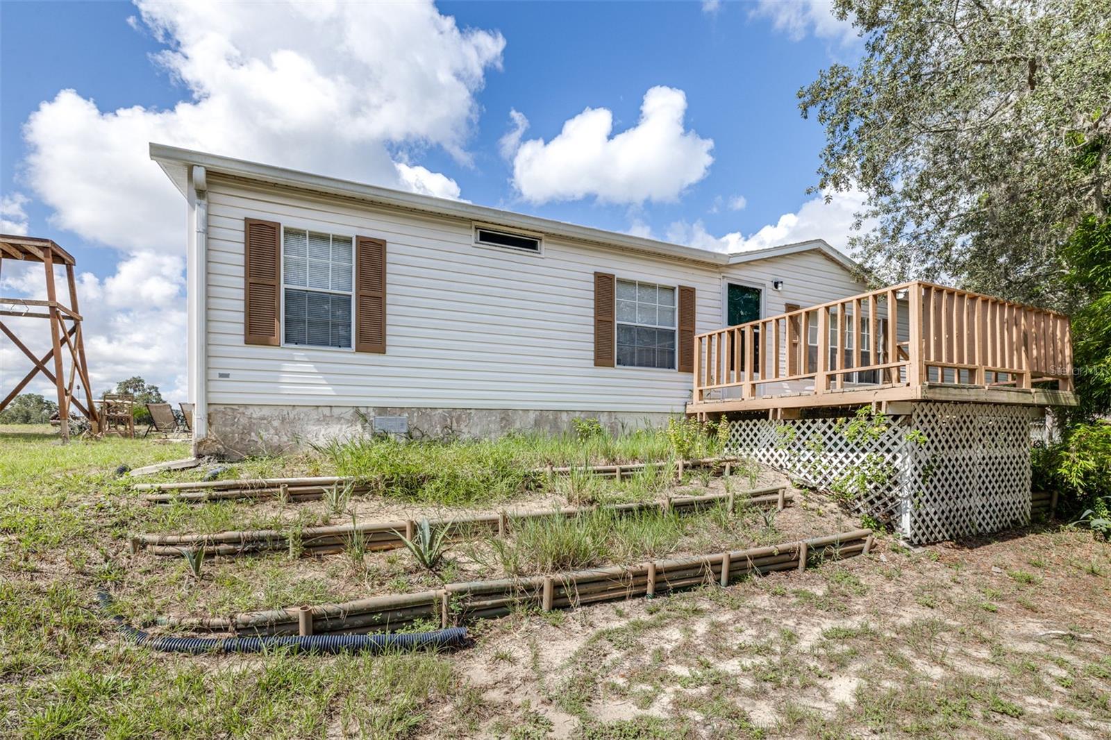 This well-maintained 1,512 sq. ft. mobile home offers comfortable living in a peaceful country setting, while still being conveniently close to Hwy 27 and I-4 for commuters.
Step inside to find luxury vinyl plank flooring throughout, a spacious eat-in kitchen with plenty of storage, and a formal dining room that can easily serve as a home office (as currently pictured). The large living room and master suite provide an open, inviting feel, while the master bath features a garden tub and walk-in shower for added comfort. An indoor laundry room adds practicality and convenience.
Enjoy outdoor living with a large covered back porch—perfect for relaxing or entertaining—and a welcoming wooden front porch. The property also includes a sizable garage/workshop, ideal for projects, storage, or hobbies.
With shade trees, full fencing, and plenty of space to spread out, this property combines charm and functionality. Whether you’re looking for a quiet retreat or a commuter-friendly location, this home offers the best of both worlds.