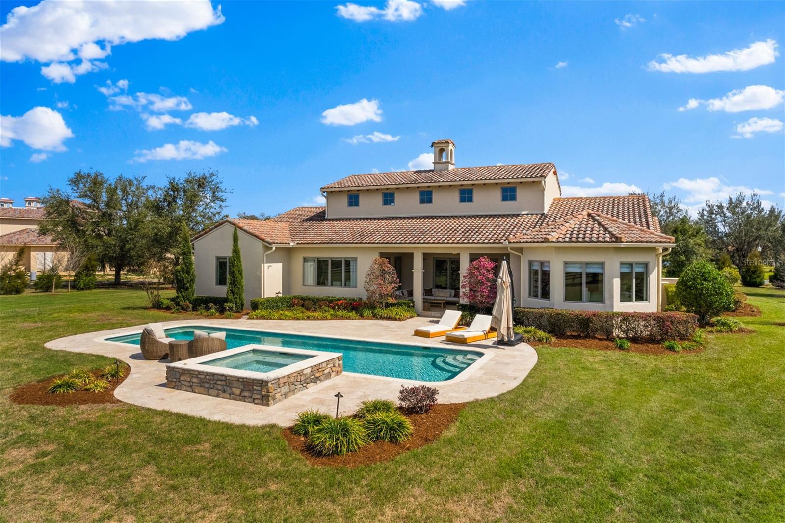 View the cinematic video and experience the ultimate in luxury living with this exquisite 5.34-acre Tuscan-style equestrian estate, nestled within a secure gated community surrounded by an expansive 8,000-acre state forest. This property offers a perfect escape, just 20 minutes from the renowned World Equestrian Center and 5 minutes from shopping, medical facilities, and dining options, conveniently situated between the Rainbow River and Ocala. This stunning 2016 move in ready furnished home provides a custom feel within the 4 bedrooms with en-suite bathrooms on the main level with an additional 5th versatile/media room on the second floor. The impressive living area is highlighted by a cathedral ceiling, a cozy gas fireplace, and an open custom-made kitchen, formal dining room, and pantry. Enjoy the western exposure sunset views overlooking the pool and pastures! The primary suite is generously sized, and the home boasts numerous closets, tray ceilings throughout, and elegant travertine finishes inside and out. With plaster walls, pre-cast trims, and over 3,800 square feet under air conditioning, this home seamlessly combines elegance and functionality. The property includes a breezeway leading to a spacious two-car garage with an upstairs room, all under air conditioning. This unique open floor plan amazing light and entertaining spaces. Enhancements to the property include a heated 41 ft x 14 ft pool and spa added in 2020, and a beautifully constructed 3-stall (14x14) center aisle concrete block barn with a tack room, full bath, and garage built in 2022. Equestrian enthusiasts will appreciate the two paddocks with automatic waterers, a 200 x 100 riding arena, and creosote board fencing. Enjoy direct access to miles of trails right from your backyard.