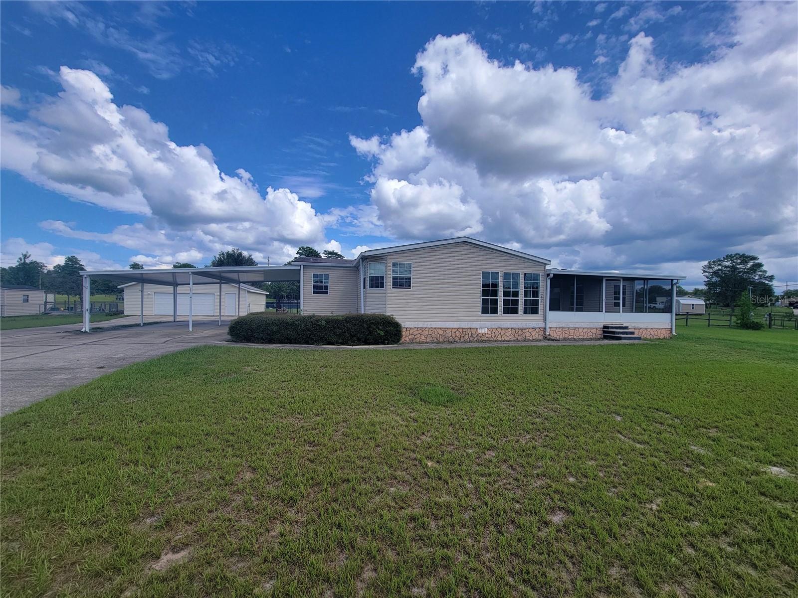 This beautifully maintained 3-bedroom, 2-bath mobile home offers comfort, space, and functionality inside and out. Step into a spacious living room featuring a cozy fireplace, perfect for relaxing evenings. The large kitchen is a cook’s dream with a center island, bar-top seating, and plenty of counter space for meal prep and entertaining. Enjoy ceiling fans throughout the home for year-round comfort. Carpeted bedrooms provide warmth and comfort, while laminate flooring in the main living areas adds style and easy maintenance.
The primary suite includes a generous master bath complete with a soaking tub, walk-in shower, and ample space for daily routines. Outdoor features include a 2-car carport, detached 2-car garage, fenced yard for privacy and pets, and a large covered rear deck—ideal for entertaining or relaxing outdoors. The screened front porch with tile flooring adds a welcoming touch and a great place to enjoy your morning coffee. Don’t miss this well-rounded home that combines comfortable living with practical features and outdoor enjoyment!