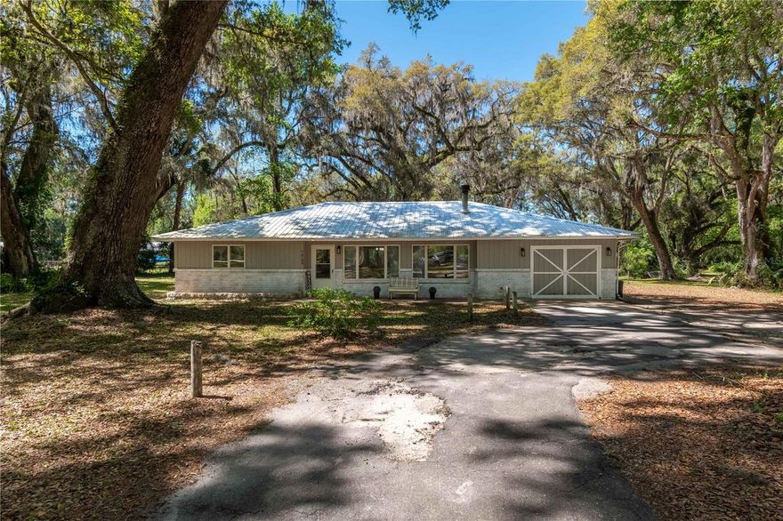 Amongst stately granddaddy oaks in the Meadowbrook Ranches neighborhood, this charming 3-bedroom, 2.5-bath home on 4.44 acres offers the perfect blend of country living and modern convenience. A circular driveway welcomes you to the property, where a cozy front patio invites you to sit back and enjoy the peaceful surroundings. Inside, natural light fills the spacious 1,992 sq. ft. home, featuring a desirable split-bedroom layout and wood-burning fireplace in the living room. Stylish wood-look luxury vinyl flooring extends throughout most of the home, complemented by laminate in select areas. The well-appointed kitchen boasts stainless steel appliances and direct access to the dining area, which features a pass-through window to the living room for effortless entertaining. A versatile bonus room—currently used as a private bar area—offers endless possibilities, whether as an office, playroom, or additional gathering space. The inviting primary suite provides a relaxing space with multiple closets and a private en-suite bath. Step outside to the screen-enclosed back patio, where a sparkling in-ground pool and covered seating area with ceiling fans create the ultimate outdoor oasis. For those seeking space for hobbies, storage, or potential equestrian use, the property features a separate three-car garage/workshop with multiple bays, offering ample room for equipment or customization. While not currently set up for horses, the A1 zoning allows for easy conversion into a mini-farm if desired. Additional updates include a metal roof (2022), a new water heater (2022), and an HVAC system with a smart thermostat (2021). Whether you're looking for a private retreat or a place to create your dream homestead, this property delivers both comfort and potential—all just a short drive from both Ocala and Gainesville!
