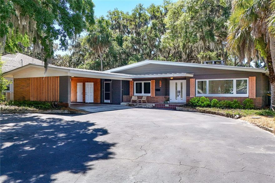 Experience mid-century modern living with serene lake views in this beautifully updated home overlooking Lake Eustis! When you first walk onto the property, you are greeted by a well-manicured lawn and a front porch that overlooks Lake Eustis, perfect for peaceful evenings watching the sunset. Inside, soaring 20-foot cathedral ceilings with exposed wooden beams, skylights, and custom windows flood the space with natural light and showcase the home’s distinctive character. The updated kitchen blends modern convenience with timeless design, featuring a stunning walnut butcher block island ideal for entertaining. It opens seamlessly into the living area, anchored by a striking brick, wood-burning fireplace. In addition to the master suite and 2 bedrooms, this home has an additional living space with built-in bookshelves and more views of Lake Eustis, and a bonus room towards the back of the home that could be used as an additional bedroom, office, or den. Stepping onto your screened-in back porch, you can take in the full refuge this backyard provides. Lush landscaping throughout gives you shade, and with a deck that leads to an above-ground hot tub, this yard is a great place to extend your hosting abilities and unwind. This home also has a 320sqft additional unit equipped with electricity, air-conditioning, and insulation. Currently prepped for a workshop and additional storage, this dwelling has the potential to be an additional living space. Located just over a mile from downtown Tavares—known as “Seaplane City”—you’ll enjoy easy access to waterfront dining, local attractions, and more. Plus, you’re approximately an hour from Orlando’s world-class theme parks and Florida’s beautiful beaches. Recent 2022 updates to this home include a metal roof, a/c, water heater, windows, marble tiling, luxury vinyl flooring, oven, dishwasher, and back deck.