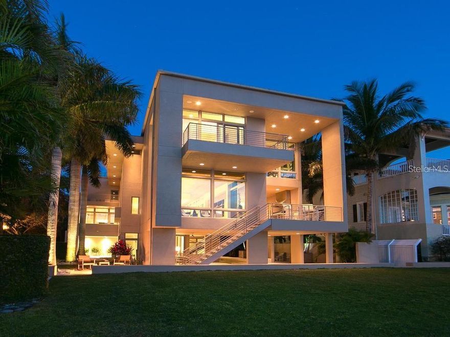 Privately positioned in gated Oyster Bay Landings with limitless water views stretching down a short canal to Sarasota Bay, this stunning iconic masterpiece from world-renowned architect Guy Peterson is a breathtaking example of the Sarasota School of Architecture’s style and vision. A comfortable modernistic ambiance flows freely throughout the 5,428 sq. ft. of open living where walls of glass capture spectacular displays of the cerulean blue water and evening skies of fiery beauty. No detail has been overlooked. No expense has been spared. Architecturally striking, this 4-bedroom, 4.5-bath waterfront residence is the ultimate indulgence offering rarity, cachet and grandeur. A shared dock with 2 lifts is conveniently situated on a waterway unencumbered by any bridge. Floor to ceiling windows frame expansive vistas and abundant natural light complements the thoughtfully-appointed and expertly-planned space. Over 4,000 square feet of outdoor area is inviting and festive, and presents unique vantage points to deliver an exhilarating experience. Expansive terraces promote seamless indoor-outdoor living. Covered entertaining is abundant among the verdant tropical gardens and immaculately manicured grounds. Resort-style amenities including an elevator, courtyard with fire pit and heated pool/spa, and breathtaking reflecting pool with fountain. The stunning kitchen is a culinary delight and complemented by an extravagant amenities package of top-tier appliances, island with seating for 6, 20-ft. long counter for 2 desk workstations, side-by-side but separate refrigerator and freezer, 2 dishwashers, and deep walk-in pantry. The family room is equipped with built-in entertainment wall and opens to a waterfront patio with outdoor cooking center. The great room has travertine floors and cypress ceiling detail, and the office provides a desk with stone countertops and plenty of solid wood cabinetry. A 400-bottle wine room is the highlight of the gaming area with wet bar, electric shades and unique glass chandelier. On the third level are spa-inspired en-suite bedrooms with custom closet systems and elevated ceilings. A 30-ft. bridge leads to the master wing highlighted by incredible water views, sitting room with morning bar, and home gym/office. The primary bath creates an immersive experience with a 16-ft. long dressing hall with a wall of built-ins and mirrors, large walk-in specialty closet, multi-faceted shower, deep soaker Jacuzzi tub, separate bidet and laundry chute. In addition, there are two laundry areas, an elevator from ground level to the 2nd and 3rd floors, Creston music and lighting system, Generac generator, and 4-car garage. In one of Sarasota’s most coveted locations along the waterfront, this home redefines coastal living is just minutes from beaches, golf, fine dining and downtown Sarasota’s beloved arts and cultural offerings. When scheduling your exclusive tour of this amazing waterfront estate, make sure to allow plenty of time for exploring its incredible features, both inside and out. It must be seen in person to be fully appreciated. Even the most discerning buyer will fall in love!