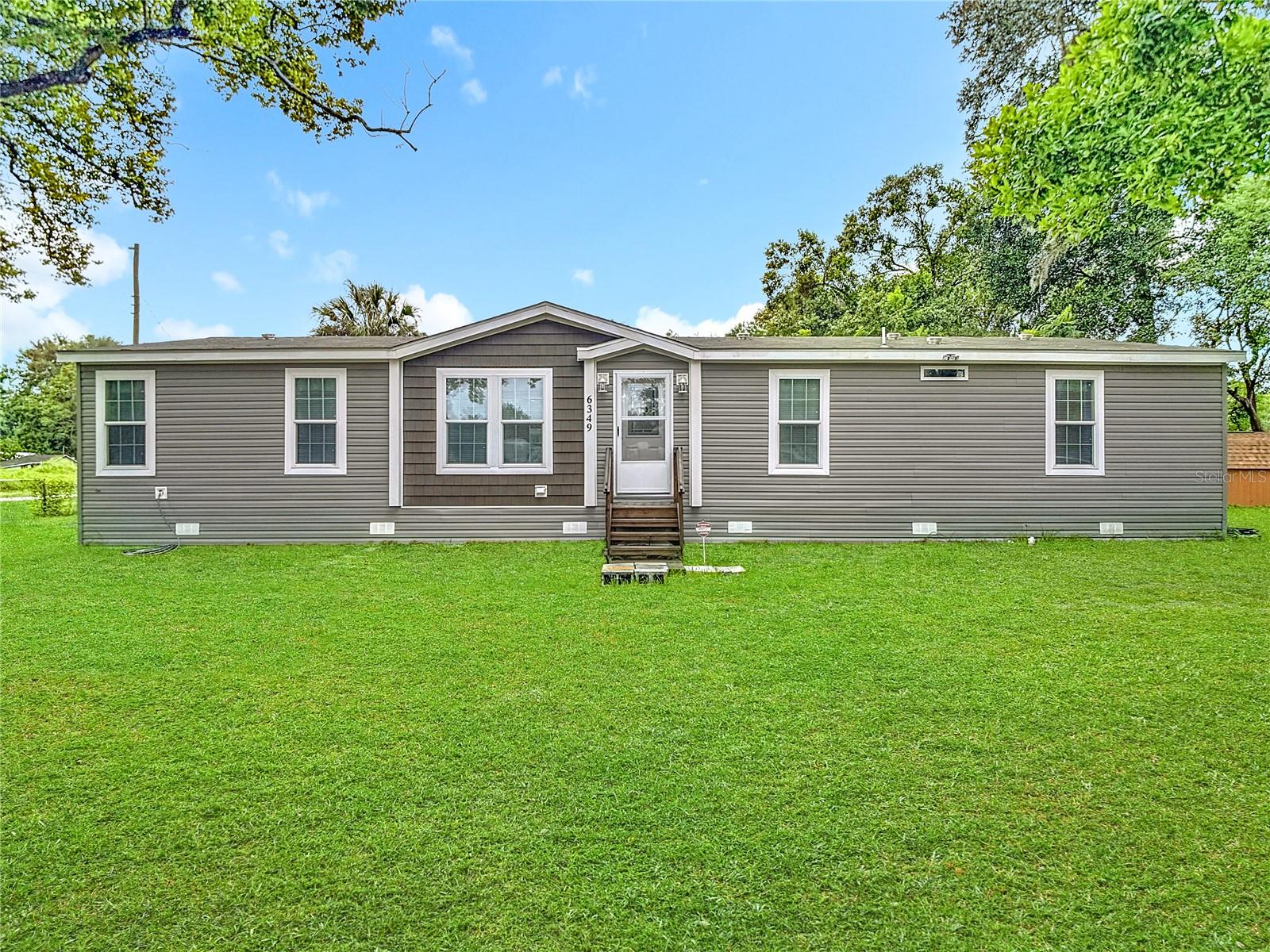 Welcome to 6349 Orris Street which is located in the charming city of Zephyrhills, Florida, known for its friendly atmosphere, picturesque landscapes, and an array of amenities. This brand-new Big-Wayne model manufactured home sits on a corner lot, with just under a .25 acre, with no HOA, and offers 4 spacious bedrooms and 2 modern bathrooms, offering a comfortable and contemporary living space. As you step inside, you'll be greeted by vaulted ceilings that enhance the open and airy feel of the home with vinyl flooring throughout. The spacious living room seamlessly flows into the kitchen and dinette area, perfect for entertaining guests. The kitchen is a chef's delight, featuring a central island with breakfast bar, shaker-style cabinets, brand-new appliances, farmhouse sink, and pantry for ample storage. The master bedroom is a serene retreat, complete with a walk-in closet and a luxurious en-suite master bath with a dual sink vanity, framed glass shower, linen closet, and water closet for added privacy. Three additional bedrooms provide plenty of space for family members or guests, each with generous closet space. A dedicated laundry room adds convenience, while the large family room offers additional space for a game room or home office. Outdoor enthusiasts will appreciate the close proximity to Zephyr Park, a local favorite featuring serene walking trails, a picturesque pond, and recreational facilities perfect for family outings and leisurely strolls. Zephyrhills boasts a vibrant downtown area, brimming with quaint shops, delicious eateries, and a host of community events that foster a strong sense of local pride. For your everyday needs, major retailers, grocery stores, and healthcare facilities are conveniently close, ensuring that you have everything you need within easy reach. Don't miss out on this incredible opportunity to own a stunning brand-new manufactured home in a prime location with no HOA! Schedule your private showing today to make 6349 Orris Street your home.