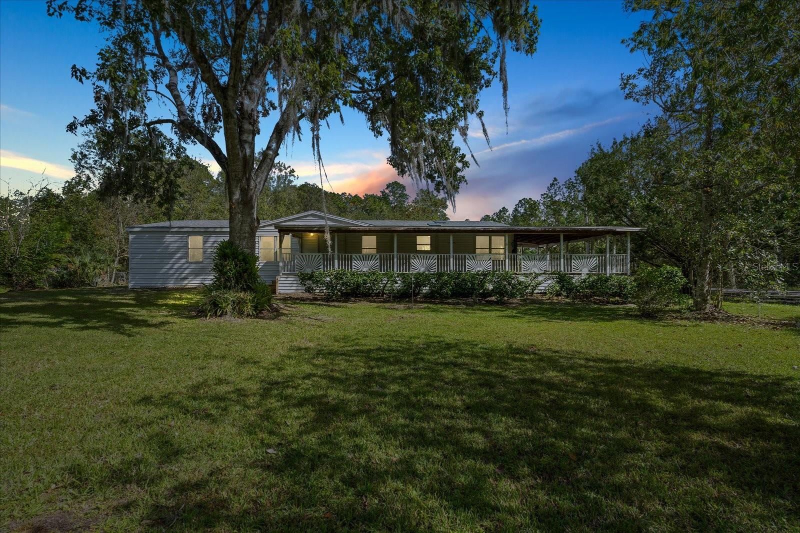 One or more photo(s) has been virtually staged. Nestled on a serene .92-acre corner lot in Bunnell, this beautifully renovated 3-bedroom, 2-bathroom manufactured home offers a peaceful retreat with ample space and privacy. Set on a sturdy concrete foundation, this home features a split bedroom floor plan with modern updates throughout, including skylights and recessed lighting that fill each room with natural light. The spacious primary suite boasts a luxurious jacuzzi tub for ultimate relaxation. Enjoy outdoor living on the expansive covered porch, perfect for entertaining or unwinding, surrounded by a yard dotted with fruit trees, including kumquat, pink grapefruit, and orange. Additional highlights include two storage sheds, a private well, and septic. This property combines comfort and charm in a quiet, secluded neighborhood with few neighbors—an ideal oasis for anyone seeking tranquility and modern convenience. Virtual Staging