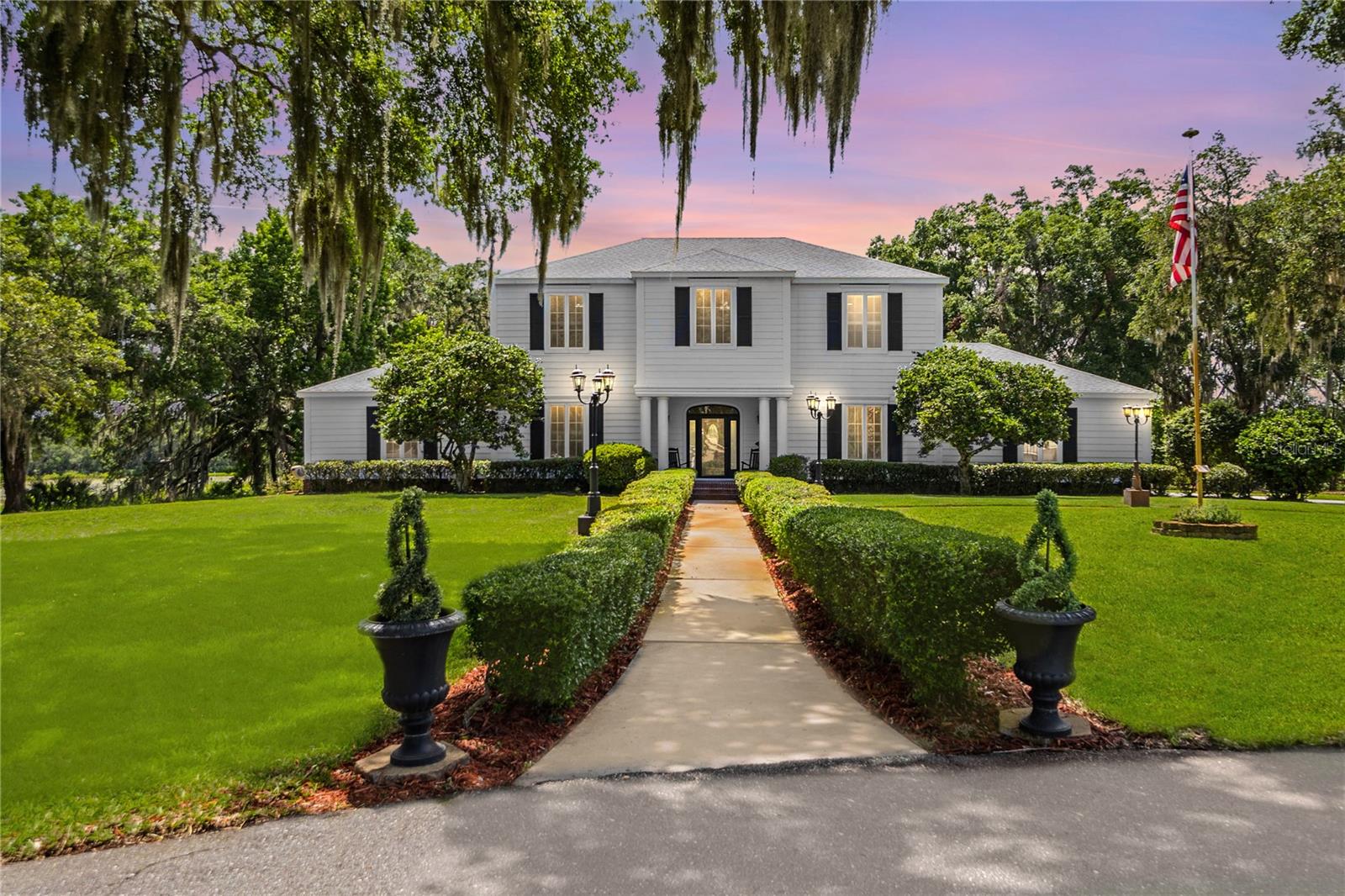 Welcome to this exceptional waterfront estate, a stunning two-story home nestled on a serene 3.59-acre peninsula at the end of a quiet cul-de-sac in a deed-restricted community. Offering 7 spacious bedrooms, 4.5 bathrooms, and an impressive 5,609 square feet of living space, this home combines timeless elegance with modern functionality. The expansive gourmet kitchen features a Viking gas range, stainless steel appliances, white wood cabinetry, granite countertops, a center island, breakfast bar, walk-in pantry, and a butler’s pantry. Built-in shelving adds a custom touch, while both a formal dining room and a bright eat-in kitchen provide ample space for entertaining. The home opens into a grand foyer leading to a formal living room with a cozy fireplace, accented by plantation shutters and crown molding. The primary suite offers its own fireplace, an enormous walk-in closet, and a spa-like bathroom complete with a garden tub, separate shower, and dual vanities. A versatile flex room provides additional space for a home office, gym, or media room. Upstairs, you’ll find a full laundry room with washer, dryer, sink, dog bath, and cabinets, with an additional laundry hookup located in the garage for added convenience. Additionally, upstairs you will find five bedrooms and two bathrooms. The 3-car side-entry garage features epoxy floors and custom cabinetry, ideal for storage and organization. Security and comfort are top priorities, with a full security system already in place. Outdoors, the property is truly a retreat, showcasing a 90x15 screened lanai overlooking a serene waterfront setting shaded by beautiful grandfather oaks. A separate shed with air conditioning provides the perfect space for a playroom, studio, or hobby area, while a designated firepit area invites relaxed evenings under the stars.
