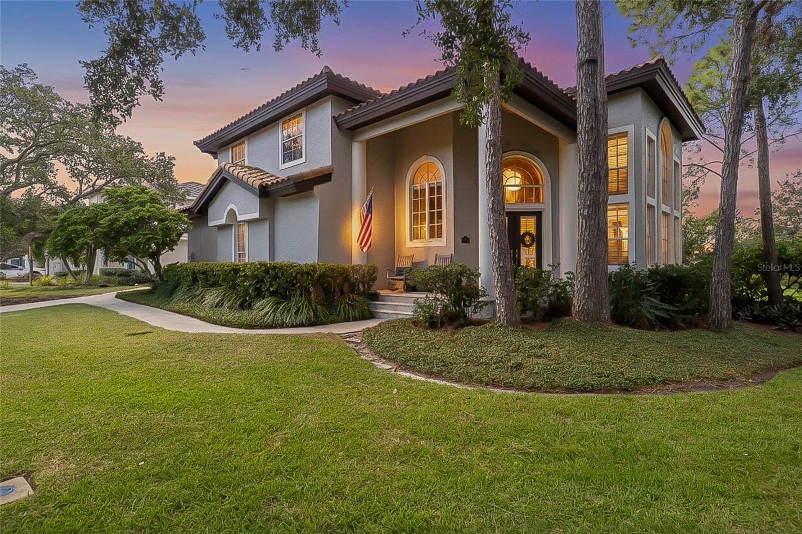 Tucked within the prestigious, guard-gated enclave of Placido Bayou, this remarkable two-story estate stands as one of the community’s most custom-designed floorplans — a true showcase of craftsmanship and coastal sophistication. Spanning over 3,500 square feet, the home features four bedrooms plus an office and two-and-a-half baths, each space thoughtfully curated for form and function. The entire first floor has been updated with rich coastal hardwood flooring and a showstopping gourmet kitchen that defines modern luxury. Every element, from the beveled Quartzite countertops to the Sub-Zero refrigerator, Wolf oven, induction cooktop, and built-in wine cooler, reflects an uncompromising standard of quality. Cleverly integrated pull-out appliance and beverage cabinets keep the space and electrical outlets discreet and functional. Opposite the large kitchen island lies an inviting hearth room which opens to a Southern-style pool terrace through French doors overlooking the lake—a picture-perfect setting for morning coffee or evening gatherings. The formal dining room and adjacent hospitality room’s soaring 30-foot ceilings create a dramatic sense of arrival, balanced by the warmth of natural light and the graceful sweep of a staircase that leads to the upper level. Upstairs, a versatile bonus room provides the ideal nook for a media lounge, creative studio, or serene space for work and study. The primary suite is a destination unto itself, featuring a brand-new, spa-inspired bathroom with chevron-laid tile, vessel tub, and a glass-enclosed shower that evokes a boutique resort. Two custom walk-in closets and a private covered balcony extend the sense of calm and luxury, offering the perfect spot to unwind among a canopy of trees. Three additional large bedrooms are located down the hall with a shared hallway bathroom. Thoughtfully designed and meticulously upgraded, this home captures the essence of refined Florida living—all while being minutes away from dining, shopping, entertainment and outdoor enjoyment of downtown St. Petersburg, sugar-sand beaches and a quick commute to two international airports.
