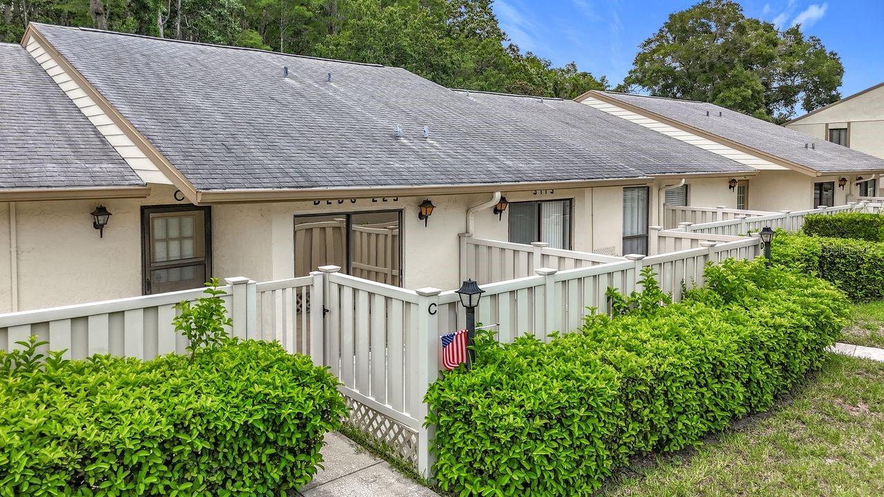Discover all that Tarpon Springs has to offer with this charming 2-BR, 2-Bath home in Pine Ridge at Lake Tarpon Village II and Deer Hollow. This home features a welcoming open floor plan designed for both relaxation and entertaining. Enter through a gated entry into a private huge front courtyard. The formal dining room provides an elegant space for family meals. The kitchen is large and features your laundry closet with new stacking washer and dryer and a food pantry. A sliding door in the kitchen leads to the patio—perfect for outdoor dining or relaxation. The spacious living room boasts abundant natural light and a sliding door that opens to a very large glass and screened sunroom with a peaceful private backyard. There is a large dry storage closet off of the porch. The generously sized primary bedroom includes a large walk-in closet and an ensuite bath. The seller will consider furnishing conveying with the purchase. The home has a new hot water heater, AC Unit and new laminate flooring. The Community amenities enhance your lifestyle with a clubhouse, a refreshing pool and spa, a meeting room, a kitchen, a grilling area, a playground, walking trails, and tennis courts. Enjoy a prime location with easy access to shopping, restaurants, medical facilities, Sponge Docks, downtown Tarpon Springs and beautiful nearby beaches. Schedule your showing today!