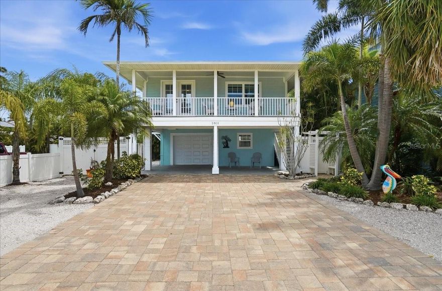 Experience the ultimate Florida beach lifestyle in this elevated 2-bedroom, 2-bathroom coastal retreat situated just steps from the pristine white sands of the Gulf. This home exudes classic island charm with modern peace of mind, featuring full impact-rated windows and doors along with durable Hardie siding designed for long-lasting beauty and protection. The exterior is anchored by a sprawling paver driveway and professional tropical landscaping, leading to a versatile covered under-house area perfect for shaded relaxation or gear storage after a day on the water. The property also boasts ample garage space that offers incredible flexibility, with plenty of room that could easily be converted into a game room or additional lounge area. Inside, the open-concept living space is bathed in natural light and anchored by rich wood flooring that flows throughout the main areas. The chef-inspired kitchen is well-appointed with warm wood cabinetry, granite countertops, and a suite of stainless steel appliances, all centered around a large breakfast bar that overlooks the dining and living zones. Offered fully furnished for the buyer’s convenience, this home is truly move-in ready and designed for immediate enjoyment. Step through elegant French doors to the expansive covered porch, an ideal setting for al fresco dining and morning coffee in the coastal breeze. Whether you are looking for a primary residence or a seasonal getaway, this turnkey coastal gem offers the rare opportunity to live life just minutes from the water’s edge.