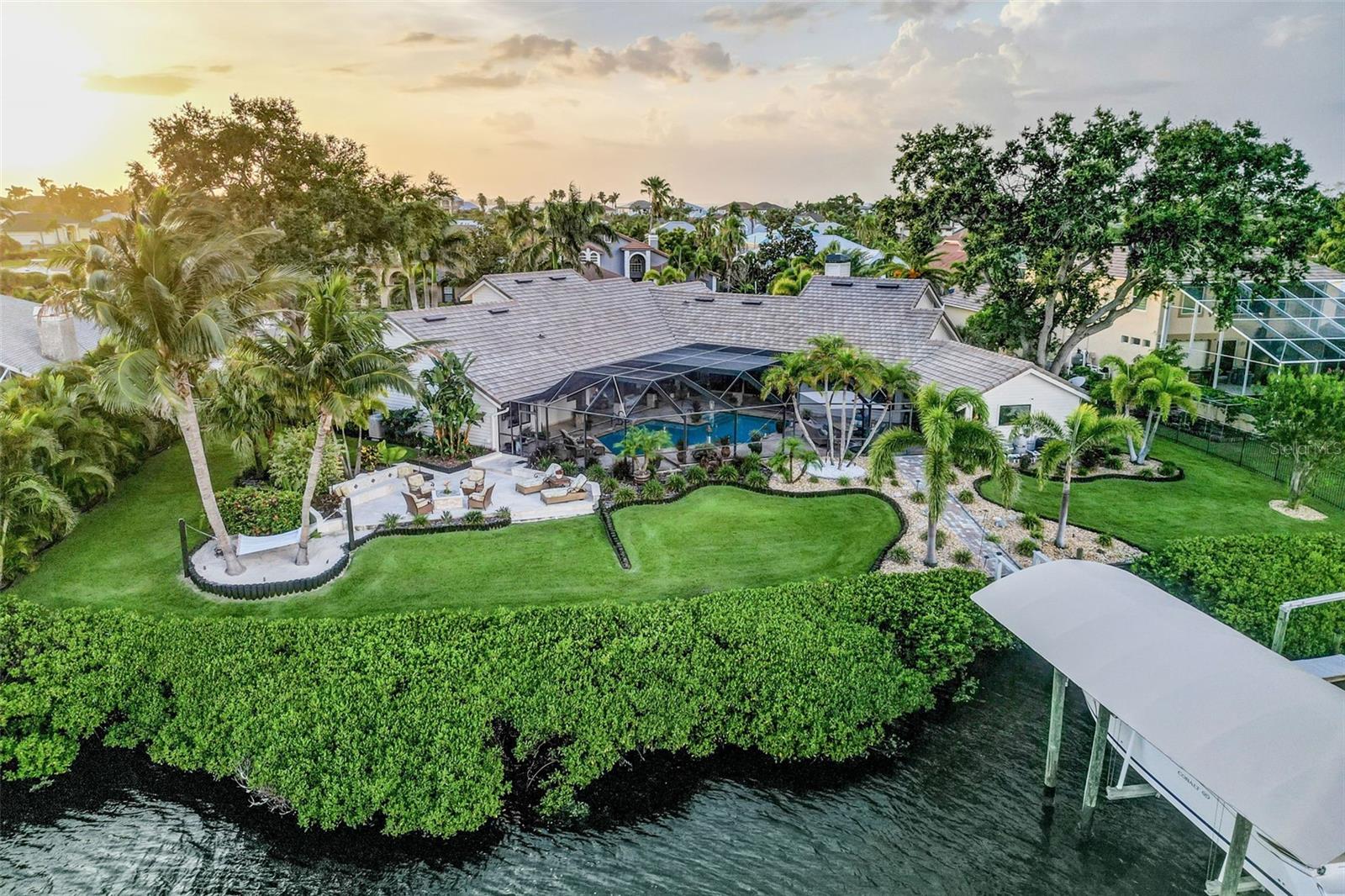 Apollo Beach Waterfront Luxury – Island Vibes, Entertainer’s Paradise & Boater’s Dream
Welcome to the epitome of Apollo Beach Luxury, a resort-style estate offering the pinnacle of waterfront living in Apollo Beach. Set on a rare double lot with 160 feet of prime canal frontage, this 4-bedroom, 3.5-bath residence spans nearly 4,000 sq. ft. of refined design—without HOA or CDD restrictions.
Inside, soaring tongue-and-groove ceilings, a stone fireplace, and open living spaces create timeless sophistication. The chef’s kitchen features quartz countertops, high-end appliances, double ovens, and a butler’s pantry. The primary suite is a private sanctuary with a spa-inspired bath, soaking tub, outdoor access, and loft retreat.
Outdoors, every day feels like a luxury vacation. Enjoy a heated 40,000-gallon saltwater pool, outdoor kitchen and bar, fire pit patio, and private hammock beach surrounded by lush tropical landscaping.
For boaters, the private dock with covered lift, jet ski lift, and direct, bridge-free access to Tampa Bay offers unmatched convenience—perfect for sunset cruises, fishing, kayaking or waterfront dining.
