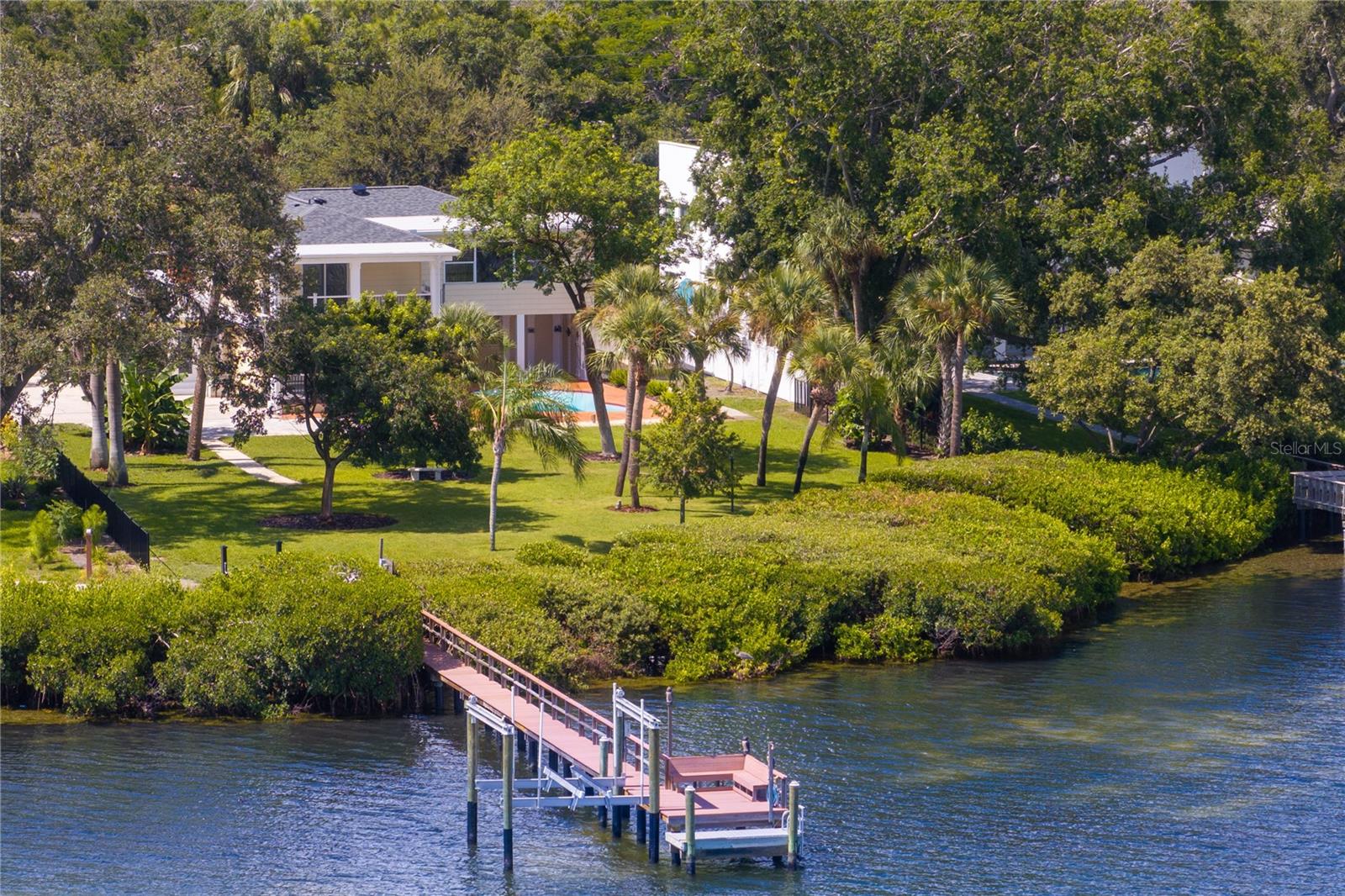 A Rare Waterfront Estate in Iconic Driftwood — A Tropical Sanctuary on Big Bayou. Welcome to one of the most extraordinary residential offerings in St. Petersburg. Nestled on over half an acre (.57 acres / 24,790 sq ft) in the coveted Driftwood neighborhood, this stately two-story, 4-bedroom, 3.5-bath home offers nearly 4,000 square feet of living space and 115 feet of direct water frontage on Big Bayou on the open waters of Tampa Bay and just minutes to downtown St Pete and the Gulf beaches of Pinellas County. Set at the end of a quiet cul-de-sac, this property is enveloped in lush tropical vegetation, offering unmatched privacy and a sense of serenity that feels worlds away—yet it’s just less than 2 miles from downtown St. Pete. As part of the exclusive Driftwood enclave—home to only 44 residences. The lot is flat and expansive, with a concrete seawall, private dock, and boat lift—all with no bridge restrictions, making this a boater’s paradise. The view is spectacular, with wide-open water vistas and a peaceful natural backdrop that feels more like a private nature preserve than a suburban setting. Inside, the home boasts great bones, classic colonial architecture, and flexible design potential. The floor plan is open and airy, designed to maximize the water views, with large windows, high ceilings, and generous room sizes. With recent updates including refinished hardwood floors, new upstairs flooring, fresh interior paint, landscaping with irrigation, and a new pool pump, the home is move-in ready while still offering opportunities for further personalization. Additional highlights include: 2025 Roof. Two wood-burning fireplaces. Whole-house water filtration system. HVAC systems (2021 and 2025). Covered balconies. Circular driveway. 8.87 ft elevation. A salt water pool and expansive backyard. Best of all, this home remained unscathed through recent hurricanes, a true testament to its solid block construction and ideal siting (8.87 elevation.) Driftwood is one of St. Petersburg’s most treasured and storied neighborhoods—a hidden gem beloved by artists, scholars, and nature lovers alike. With its storybook streets, towering oaks, and old Florida charm, it truly feels like the setting of a classic film—a magical, movie-set lifestyle right here in Pinellas County. Whether your style leans modern, transitional, or traditional Boca Grande coastal, this property is a rare canvas to create your waterfront dream home. Come experience the unmatched beauty and soul of Driftwood. This is more than a home—it’s a lifestyle, a sanctuary, and an opportunity that rarely comes along.