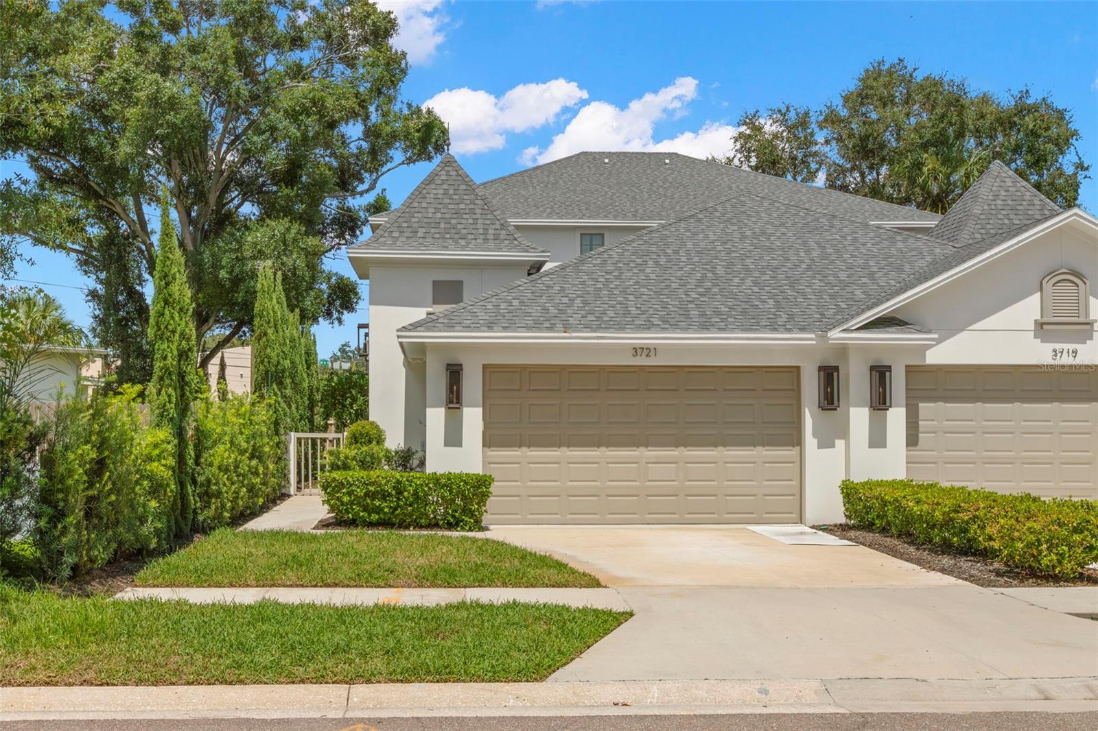 Welcome to this Magnolia Heights townhome by Canopy Builders, a French-inspired residence designed for those who value elegance, lifestyle, and luxury. Completed in 2023, this two-story property offers 4 bedrooms, 3.5 bathrooms, and over 2,200 sq. ft. of elevated living in the heart of a vibrant St. Petersburg community.
The exterior showcases Bourbon Street copper lighting, professional landscaping, and pavered verandas with exposed ceiling beams—delivering timeless appeal. A two-car garage and buried gas/electrical lines for a future pool add both utility and foresight.
Inside, 10-ft ceilings set the tone for a space highlighted by solid oak flooring, statement lighting, and upscale finishes throughout. The chef’s kitchen features a Calcutta Monet Gold quartz island, marble backsplash, 10-ft custom cabinetry with oven hood, and a marble ledger wine wall—paired with a KitchenAid appliance package. Entertaining flows naturally between the indoor and outdoor living areas.
The first-floor primary suite offers a private retreat with a 10-ft marble wet room featuring a soaking tub and frameless glass shower, followed by a custom closet designed for organization and style. Each bathroom is elevated with quartz counters, floor-to-ceiling tile, frameless shower glass, and carefully curated fixtures. Upstairs, a loft/study area and a laundry room with Noir marble floors provide added convenience. Smart living is available with Ion technology wiring for Ethernet and security.
Situated just minutes from vibrant Downtown St. Pete, residents enjoy easy access to dining, arts, waterfront parks, and entertainment—all within the charm of Magnolia Heights.