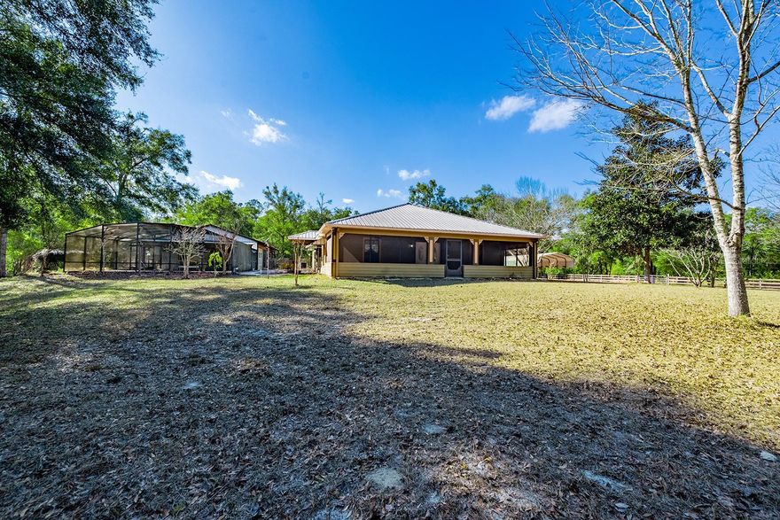 This 2-bedroom, 2-bathroom home is located on 10 acres in Bell, Florida, offering space, privacy, and a true country setting in Gilchrist County. The living room features a wood-burning fireplace and custom built-in shelving. Large bedrooms and an open-concept kitchen and dining area with a center island and pantry provide a functional layout with plenty of room. The property includes a screened front porch, an in-ground pool with screened enclosure, outdoor kitchen, and a pole barn for equipment or storage. The land is fenced and suitable for animals. A utility building has been converted into a guest house, providing additional space for visitors or extended family. Located in Bell, this property offers a quiet rural lifestyle with convenient access to local schools, shopping, and nearby rivers, springs, and outdoor recreation common to North Florida.
